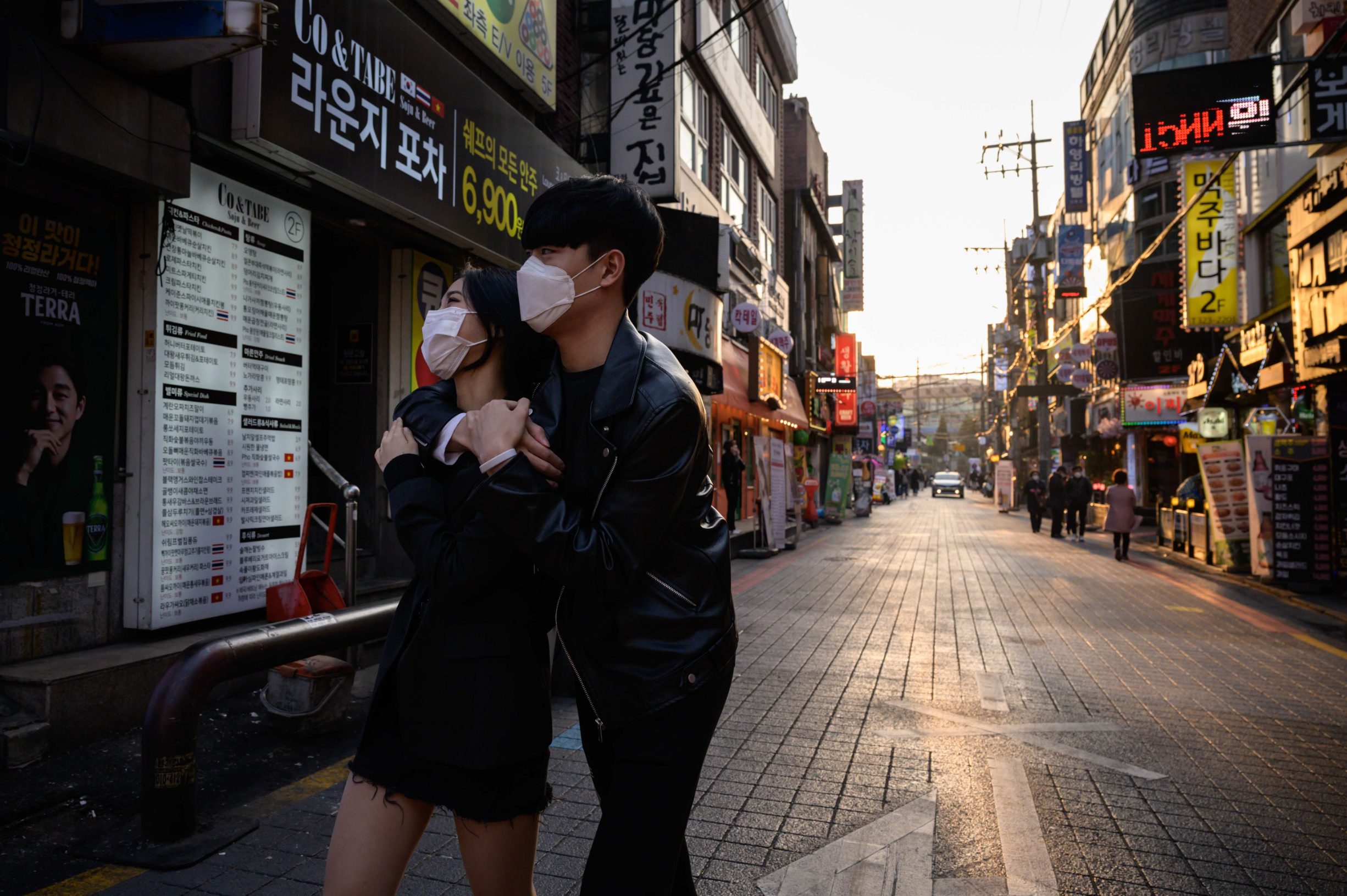 People wearing face masks amid concerns over the COVID-19 novel coronavirus, walk through an alleyway in Seoul on Marh 24, 2020. (Photo by Ed JONES / AFP)