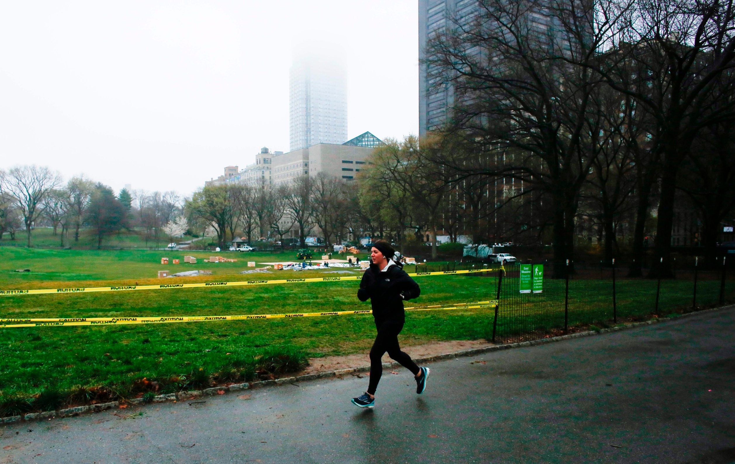 A woman jogs by Central Park as workers set up a camp in front of Mount Sinai West Hospital on March 29, 2020 in New York City. - A senior US scientist issued a cautious prediction March 29, 2020 that the novel coronavirus could claim 100,000 to 200,000 lives in the United States. Dr. Anthony Fauci, who leads research into infectious diseases at the National Institutes of Health, told CNN that models predicting a million or more deaths were 
