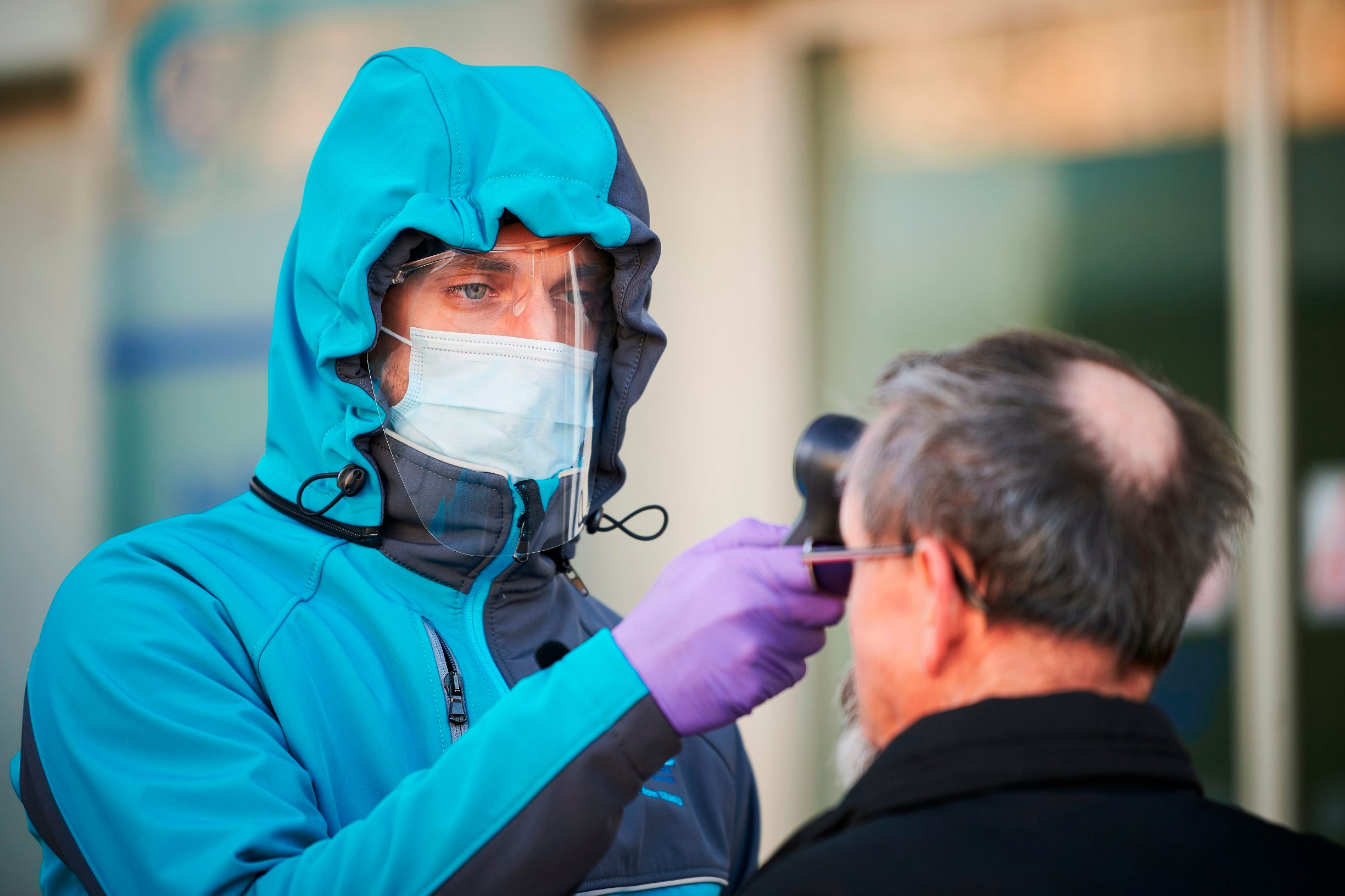 TOPSHOT - A medical worker measures body temperature at one of the entrances of the Community Health Centre in Kranj, Slovenia on March 23, 2020 amid concerns over the spread of the COVID-19 coronavirus. (Photo by Jure Makovec / AFP)