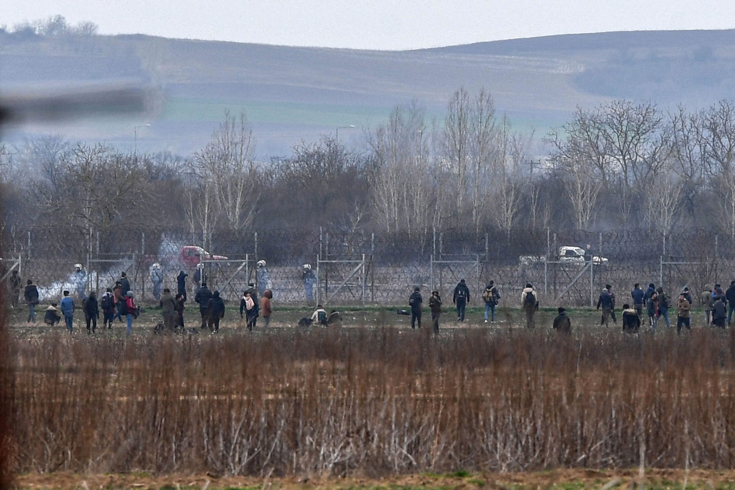 Migrants walk clash with Greek police as they resumed efforts to enter europe next to the fences near Pazarkule border gate in Edirne as Greek Police use tear gas and guns on March 4, 2020. - Migrants and refugees clashed with Greek police on the Turkish border on March 4, 2020, as they resumed efforts to enter Europe, leaving at least one person injured according to AFP correspondents. (Photo by Ozan KOSE / AFP)