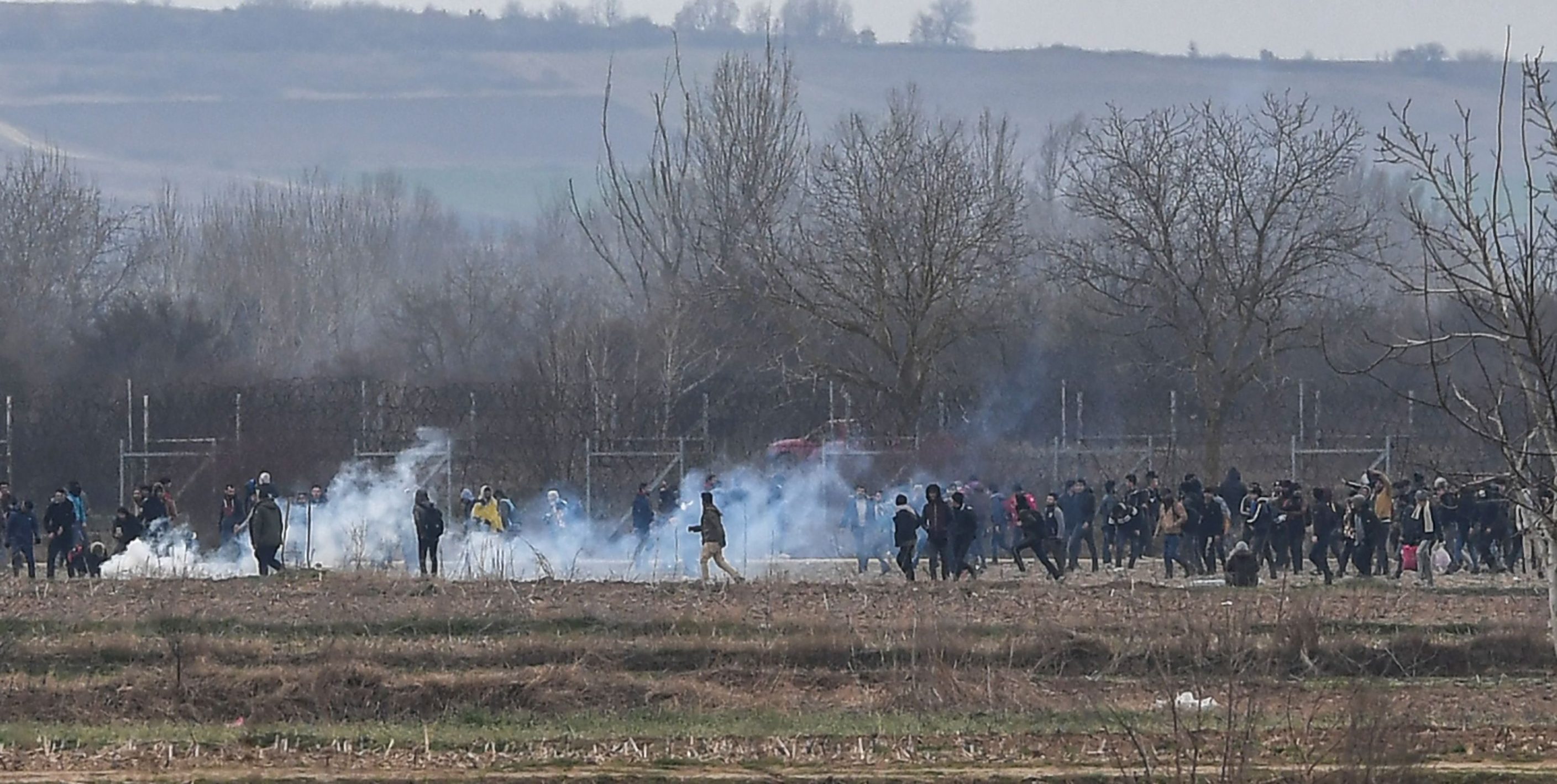 Migrants walk clash with Greek police as they resumed efforts to enter europe next to the fences near Pazarkule border gate in Edirne as Greek Police use tear gas and guns on March 4, 2020. - Migrants and refugees clashed with Greek police on the Turkish border on March 4, 2020, as they resumed efforts to enter Europe, leaving at least one person injured according to AFP correspondents. (Photo by Ozan KOSE / AFP)
