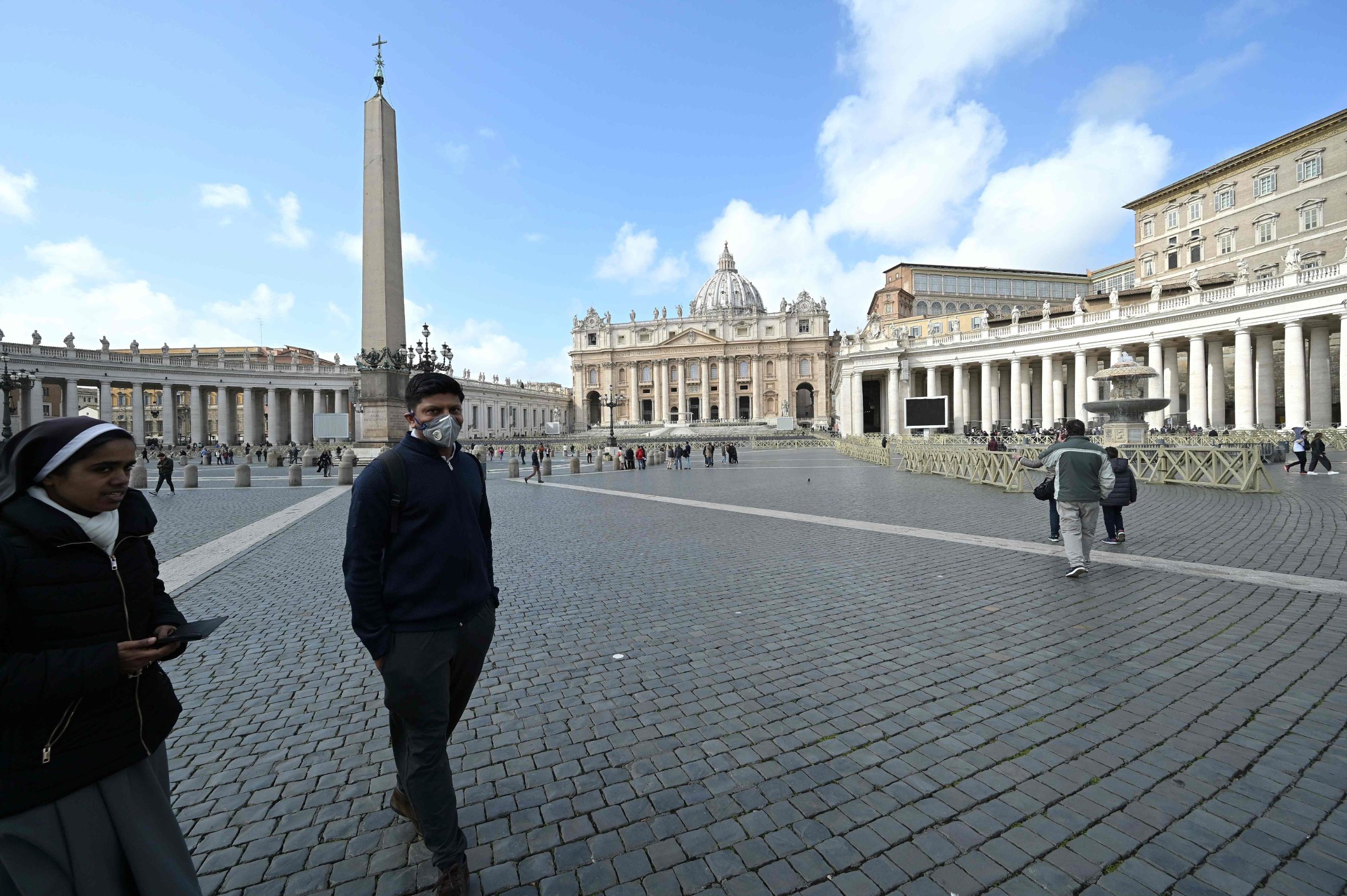 A man wearing a protective mask and a nun walk in a deserted St. Peter's square at the Vatican on March 6, 2020. - The Vatican on March 6 reported its first coronavirus case, saying it had suspended outpatient services at its health clinic after a patient tested positive for COVID-19. (Photo by Vincenzo PINTO / AFP)