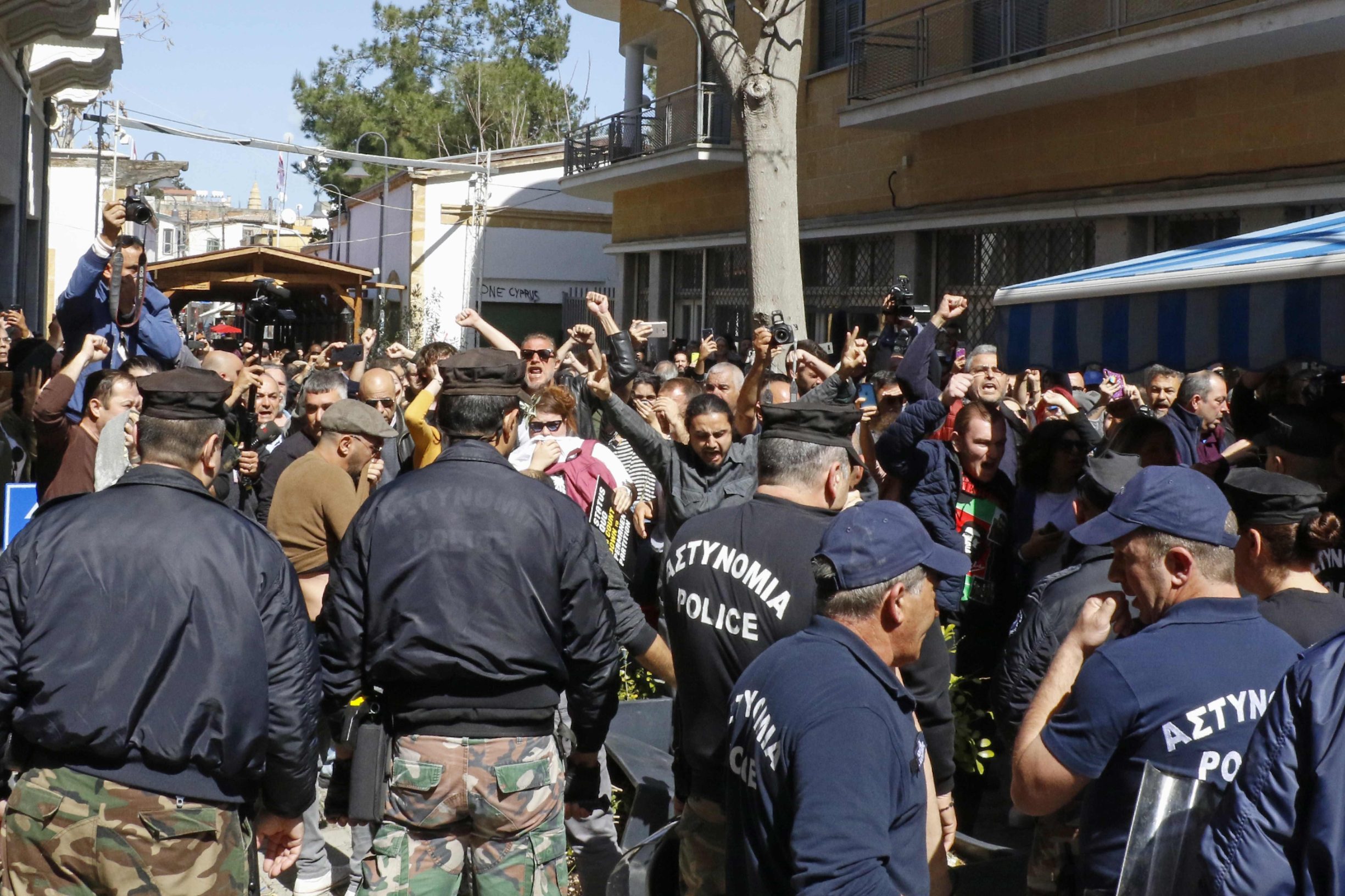 Protesters clash with Cypriot police during a demonstration on either side of the Ledra Street crossing in central Nicosia on March 7, 2020, against the closure of crossings on the divided island's ceasefire line over coronavirus fears. - Cyprus police used teargas to disperse hundreds of protesters demonstrating against the closure of crossings on the divided island's ceasefire line over coronavirus fears. A police spokesperson said four officers were injured in the capital Nicosia during scuffles with demonstrators in which police made 