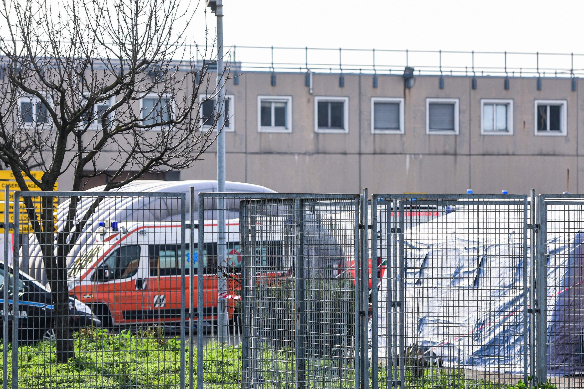 A general view shows an ambulance and a tent inside the SantAnna prison in Modena, Emilia-Romagna, in one of Italy's quarantine red zones on March 9, 2020. - Inmates in four Italian prisons have revolted over new rules introduced to contain the coronavirus outbreak, leaving one prisoner dead and others injured, a prison rights group said on March 8. Prisoners at jails in Naples Poggioreale in the south, Modena in the north, Frosinone in central Italy and at Alexandria in the northwest had all revolted over measures including a ban on family visits, unions said. (Photo by Piero CRUCIATTI / AFP)