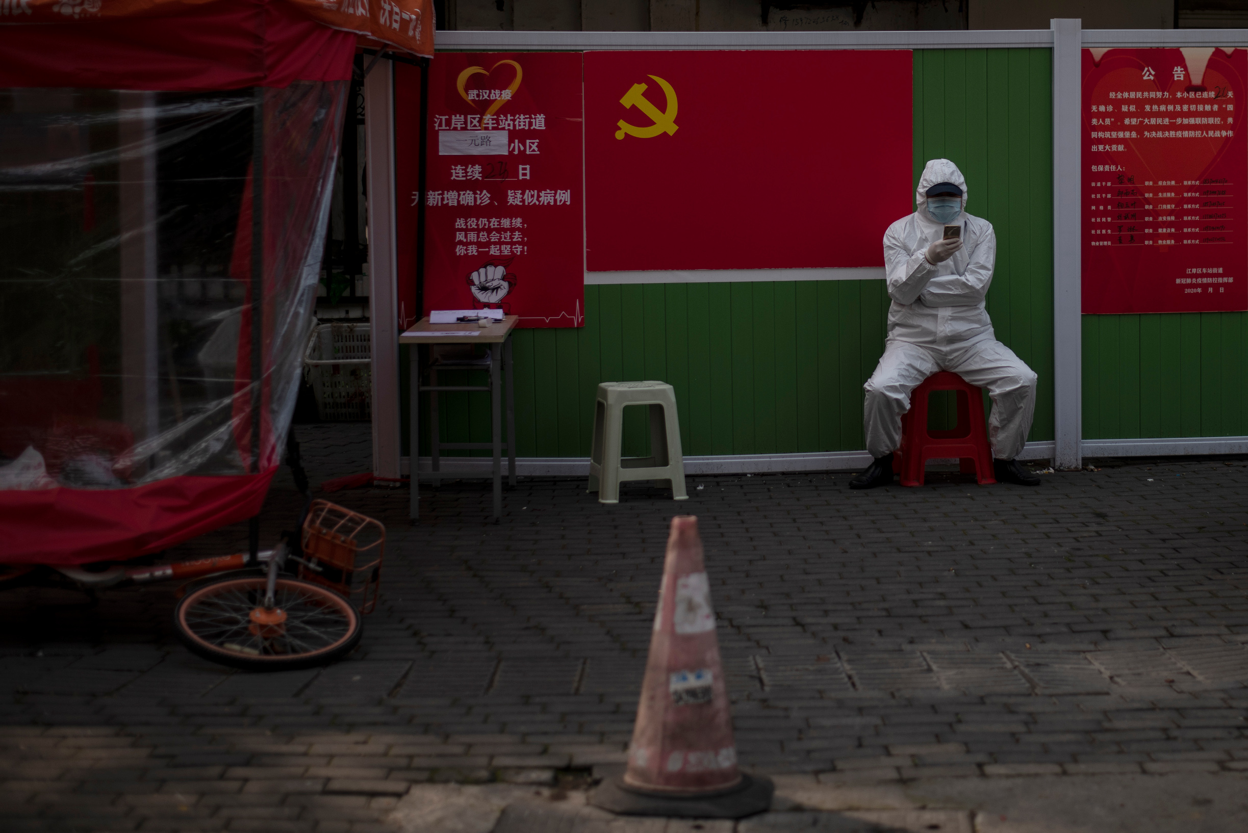 A community volunteer wearing a hazmat suit guards the entrance of a compound along in Wuhan, in China's central Hubei province on April 1, 2020. (Photo by NOEL CELIS / AFP)