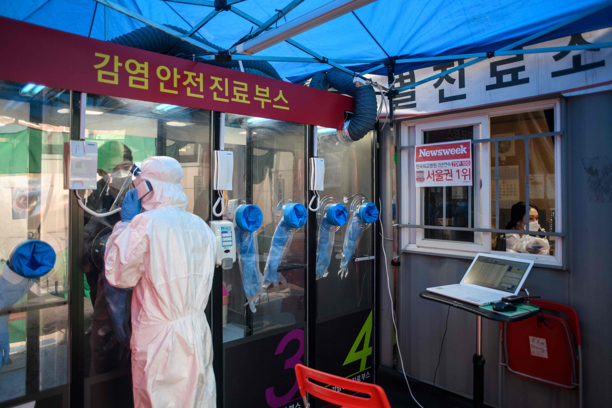 (FILES) In this file photo taken on March 17, 2020, a man speaks to a nurse during a COVID-19 novel coronavirus test at a testing booth outside Yangji hospital in Seoul. - As the coronavirus pandemic sparks global lockdowns, life has continued comparatively unhindered in places like Taiwan, South Korea and Hong Kong after their governments and citizens took decisive early action against the unfolding crisis. (Photo by Ed JONES / AFP)