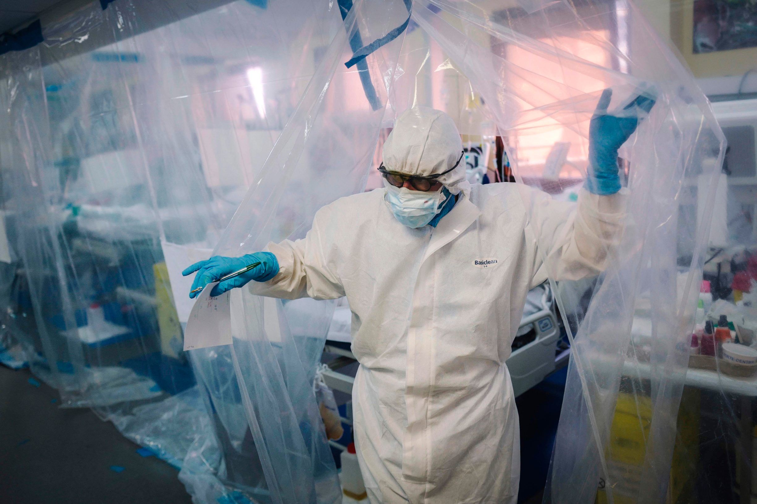 A medical staff member exits a room protected by a transparent tarpaulin after taking care of a patient infected with COVID-19 at the intensive care unit of the Franco-Britannique hospital in Levallois-Perret, northern Paris, on April 9, 2020. (Photo by LUCAS BARIOULET / AFP)