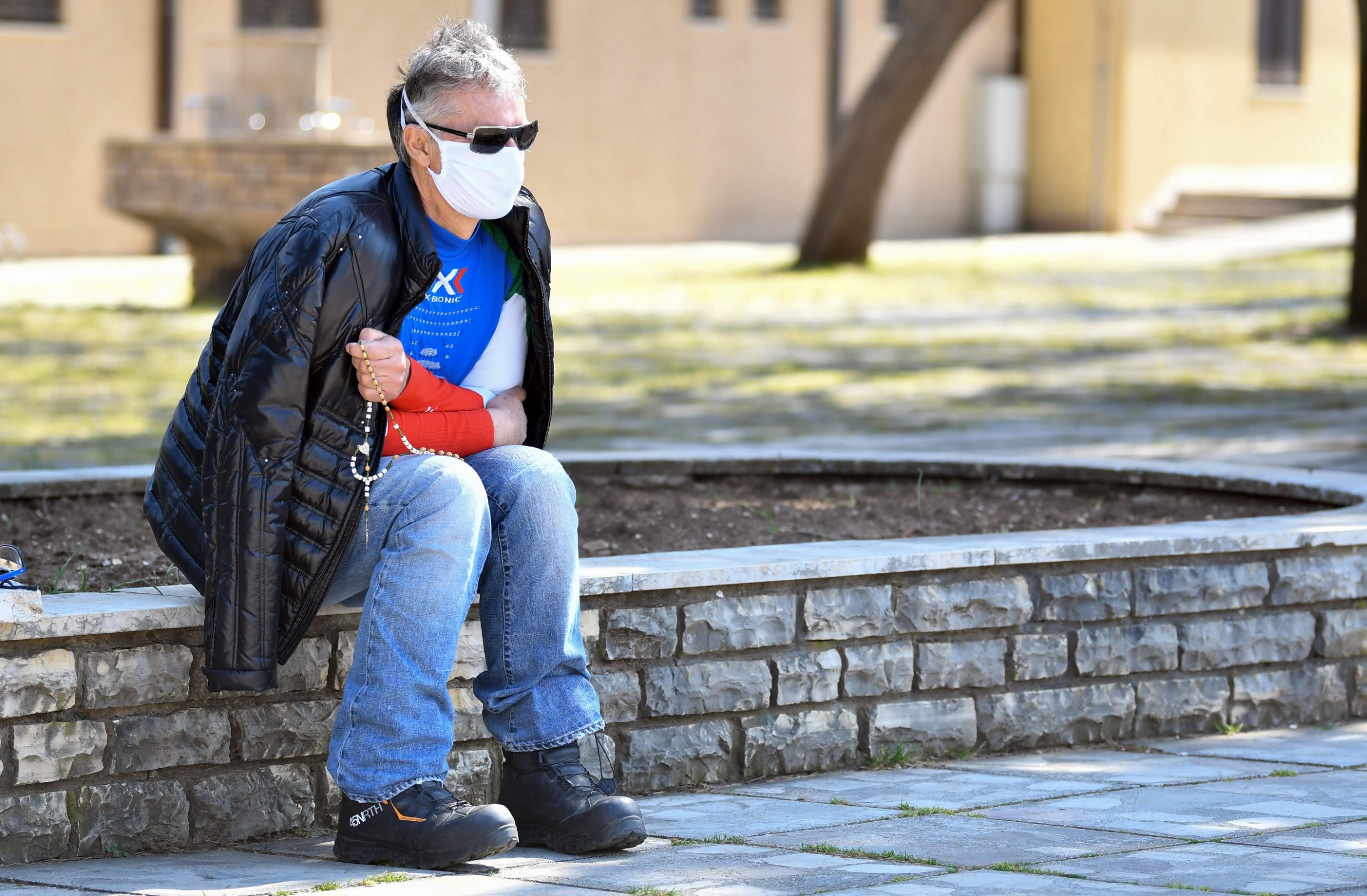 Italian citizen Gino who lives in Bosnia, prays alone in front of the St Jacob church, usually riddled with thousands of Catholic believers, at Marian pilgrimage site, in the southern Bosnian town of Medjugorje, on April 7, 2020 during a lockdown to stop the spread of COVID-19 (novel coronavirus). - Ever since the Virgin Mary was said to appear before six teenagers on a hill in Bosnia four decades ago, pilgrims have flocked to the town of Medjugorje, eager to witness a miracle. (Photo by ELVIS BARUKCIC / AFP)