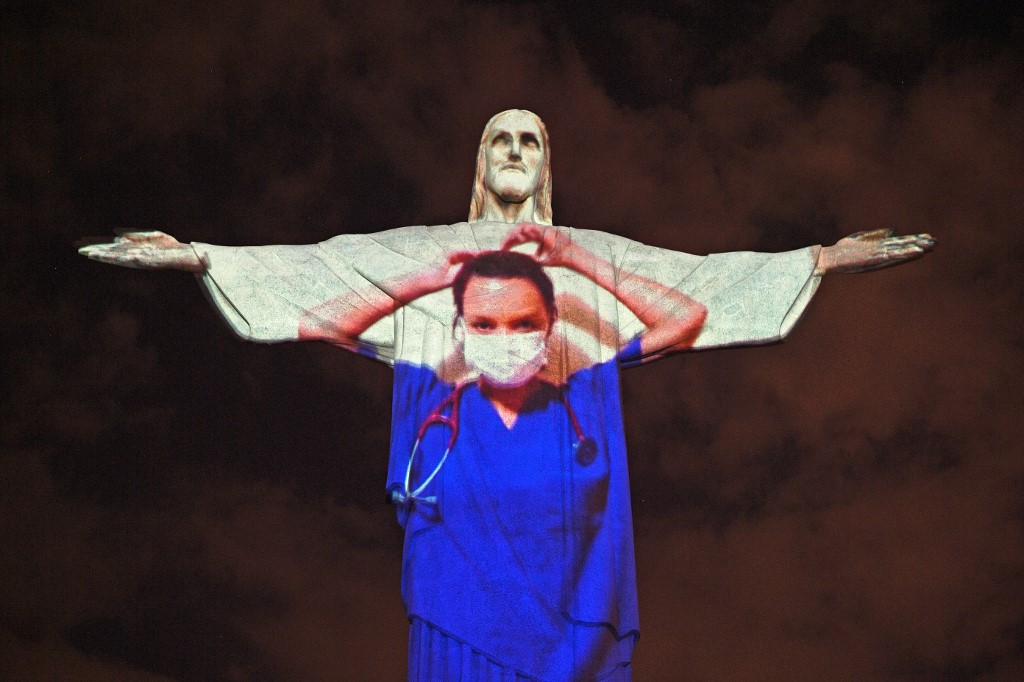 View of the world famous Christ the Redeemer statue on Easter day with a medical worker projected on it  in honour of all the medical staff fighting the COVID-9 coronavirus pandemic worldwide in Rio de Janeiro, Brazil on April 12, 2020. (Photo by CARL DE SOUZA / AFP)