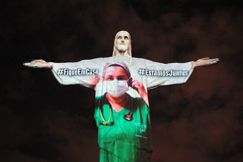 View of the world famous Christ the Redeemer statue on Easter day with a medical worker projected on it  in honour of all the medical staff fighting the COVID-9 coronavirus pandemic worldwide in Rio de Janeiro, Brazil on April 12, 2020. (Photo by CARL DE SOUZA / AFP)