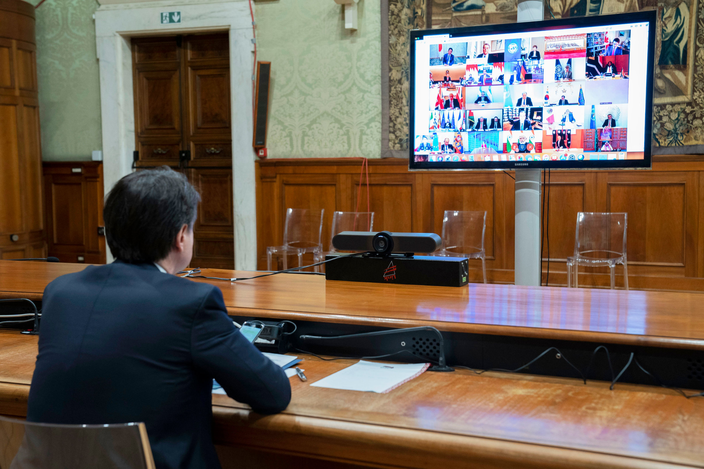 This photo taken and handout by the press office of Palazzo Chigi on March 26, 2020 shows Italian Prime Minister, Giuseppe Conte (L) taking part in a video conference as part of an extraordinary meeting of G20 leaders, from the Chigi Palace in Rome, during the country's lockdown following the COVID-19 new coronavirus pandemic. - Italian Prime Minister Giuseppe Conte is blocking a joint response that EU leaders are trying to put together to the coronavirus crisis, an Italian government source said on March 26. (Photo by Handout / Palazzo Chigi press office / AFP) / RESTRICTED TO EDITORIAL USE - MANDATORY CREDIT 