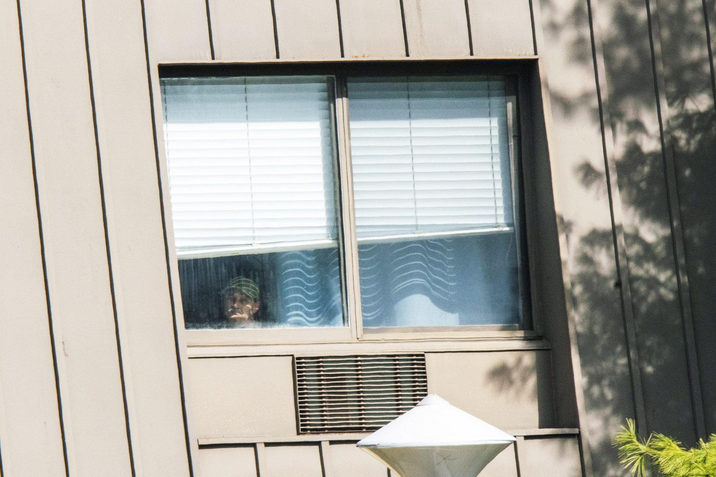 ANDOVER, NJ - APRIL 16: A man looks out from his window at Andover Subacute and Rehabilitation Center on April 16, 2020 in Andover, New Jersey. After an anonymous tip to police, 17 people were found dead at the long-term care facility, including two nurses, where at least 76 patients and 41 staff members have tested positive for COVID-19.   Eduardo Munoz Alvarez/Getty Images/AFP
== FOR NEWSPAPERS, INTERNET, TELCOS & TELEVISION USE ONLY ==