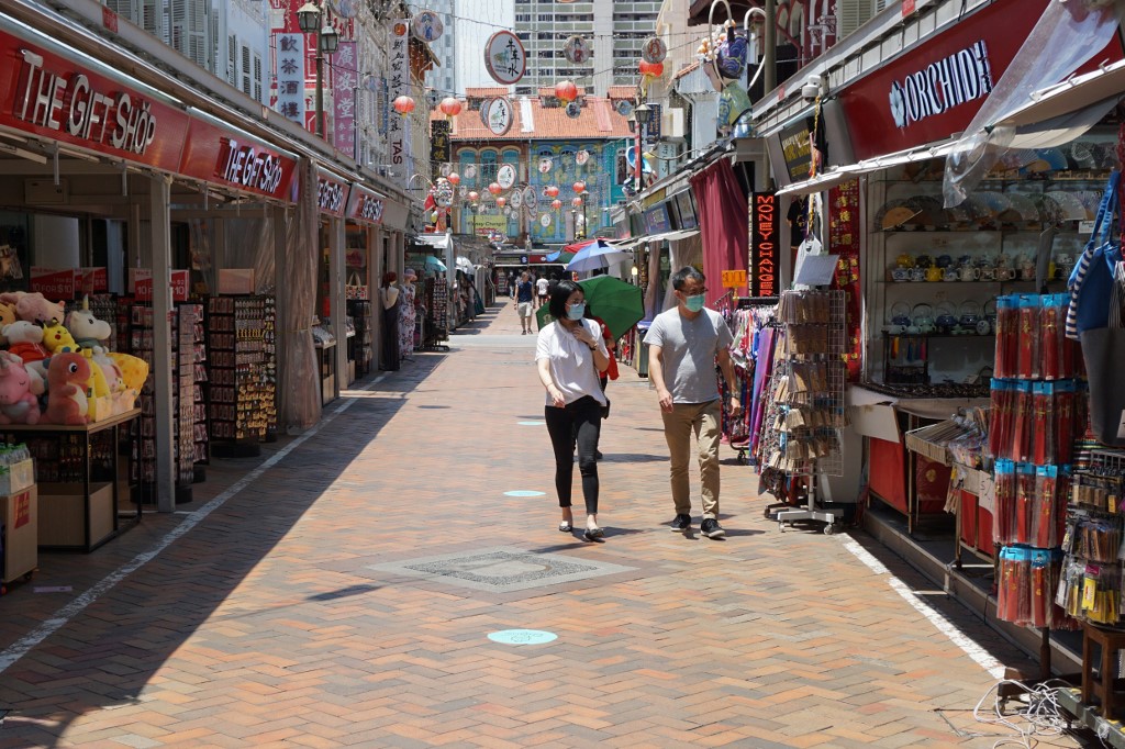 People wearing face masks as a preventive measure against the spread of the COVID-19 novel coronavirus walk past shops in Chinatown in Singapore on April 1, 2020. (Photo by Roslan RAHMAN / AFP)
