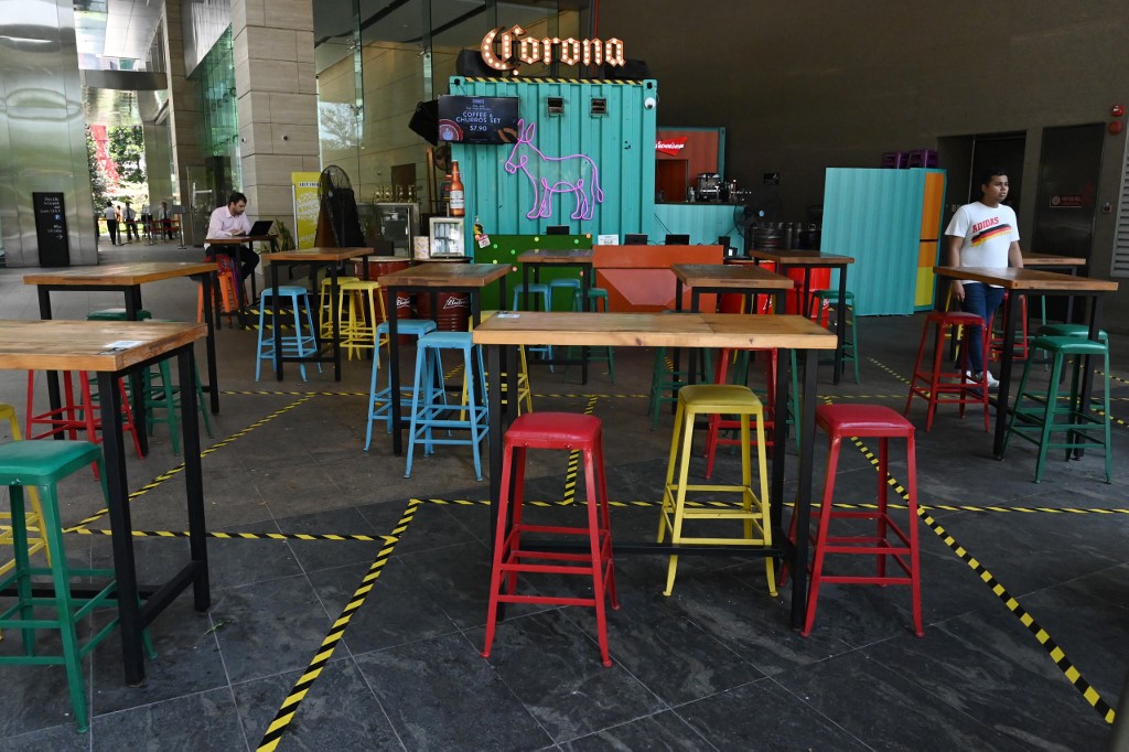 A man uses his laptop at an empty restaurant in Marina Bay in Singapore on April 2, 2020, as the government slowly tightens restrictions to combat the spread of the COVID-19 novel coronavirus. (Photo by Roslan RAHMAN / AFP)