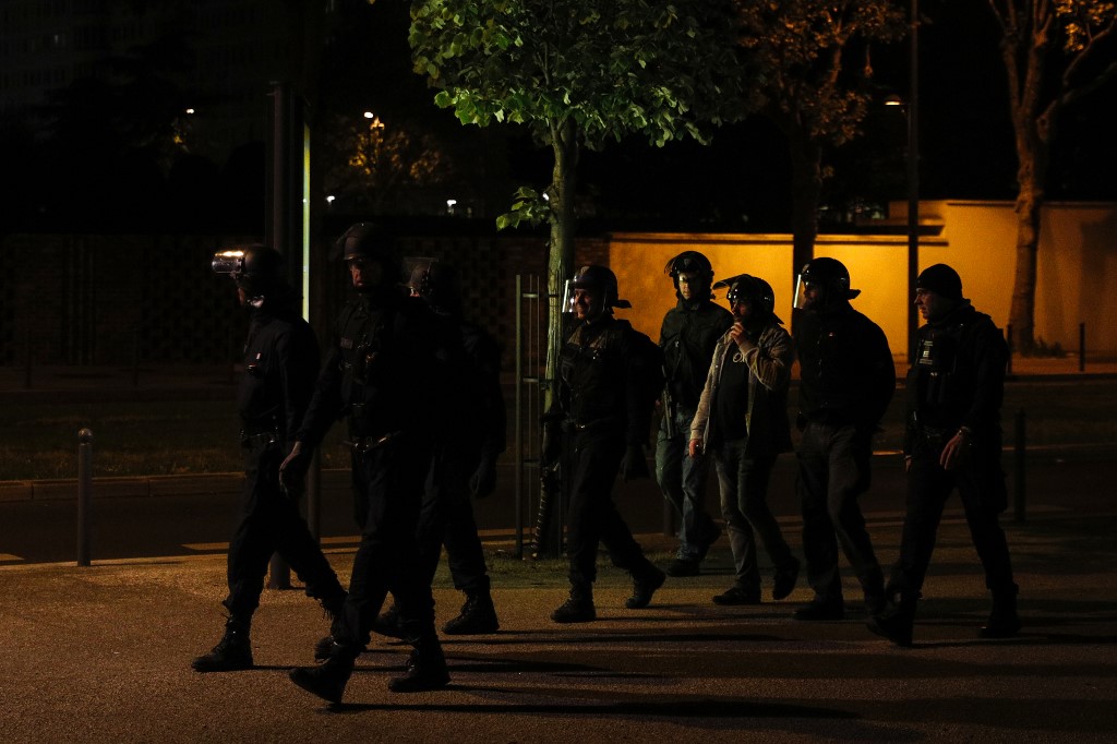 Plainclothes police and CRS anti-riot police officers walk in Villeneuve-la-Garenne, in the northern suburbs of Paris, early on April 20, 2020. - Tension with the police erupted again on the evening of April 19 in Villeneuve-la-Garenne near Paris, where a motorcycle accident involving the police had provoked the first clashes with residents the day before. (Photo by GEOFFROY VAN DER HASSELT / AFP)