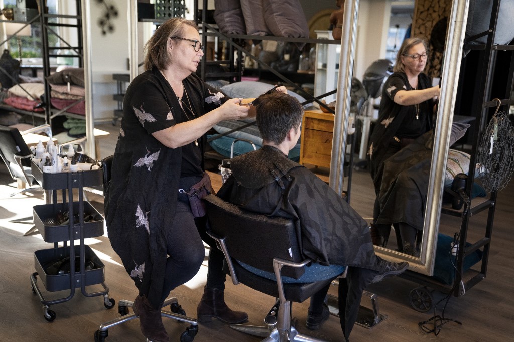 Christel Lerche at Hairdresser Hot N Tot reopens and welcomes the first customers, in Bagsvaerd near Copenhagen, April 20, 2020, amid the new coronavirus COVID-19 pandemic. - There is a pause before and after each customer and the hairdressers have permanent workstations. Customers wait for a good distance and every plastic shackle for customers' outerwear is thrown in the trash after use. Parts of Europe hit hard by the deadly coronavirus pandemic took tentative steps towards resuming normal lives on April 20, 2020. (Photo by Liselotte Sabroe / Ritzau Scanpix / AFP) / Denmark OUT