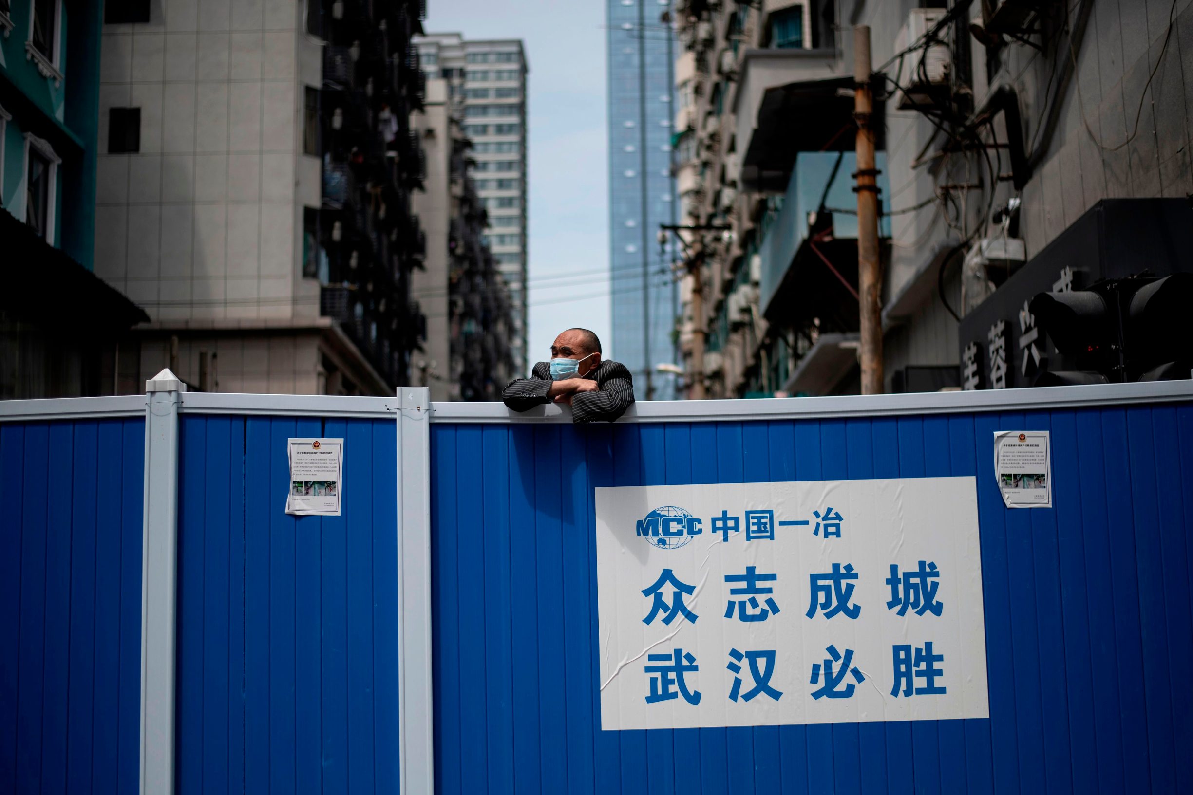 A man wearing a face mask looks over a barricade set up to keep people out of a residential compound in Wuhan in China's central Hubei province on April 14, 2020. (Photo by NOEL CELIS / AFP)