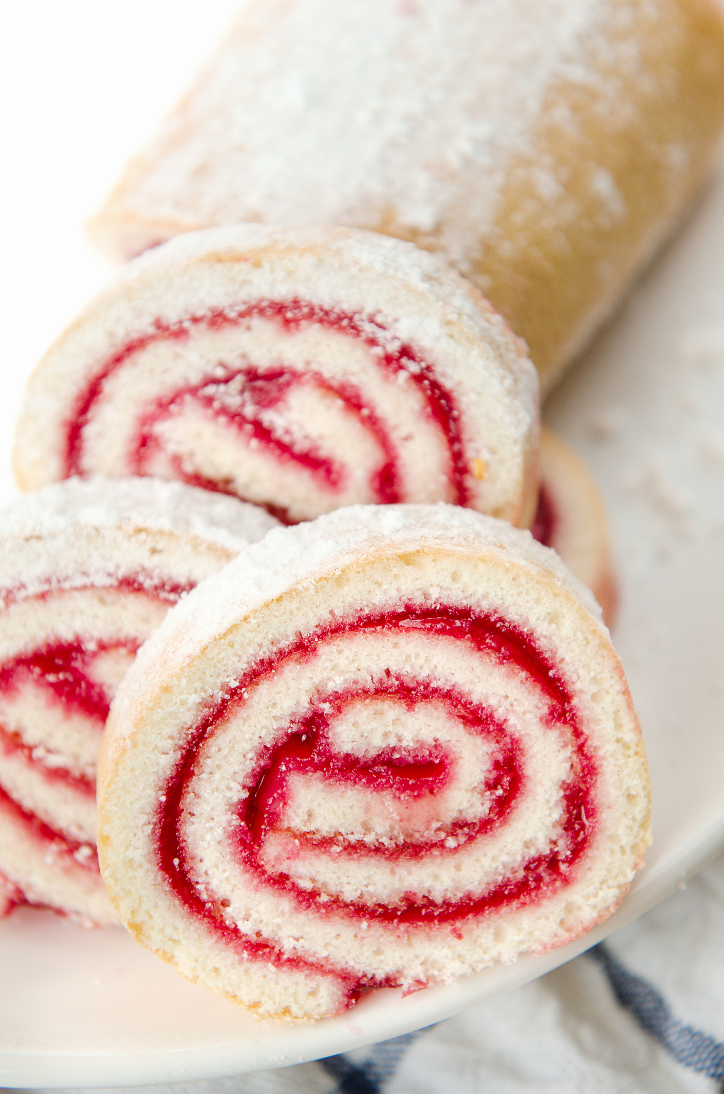 Fresh sweet roll with strawberry jam and powdered sugar on a plate and a white towel
