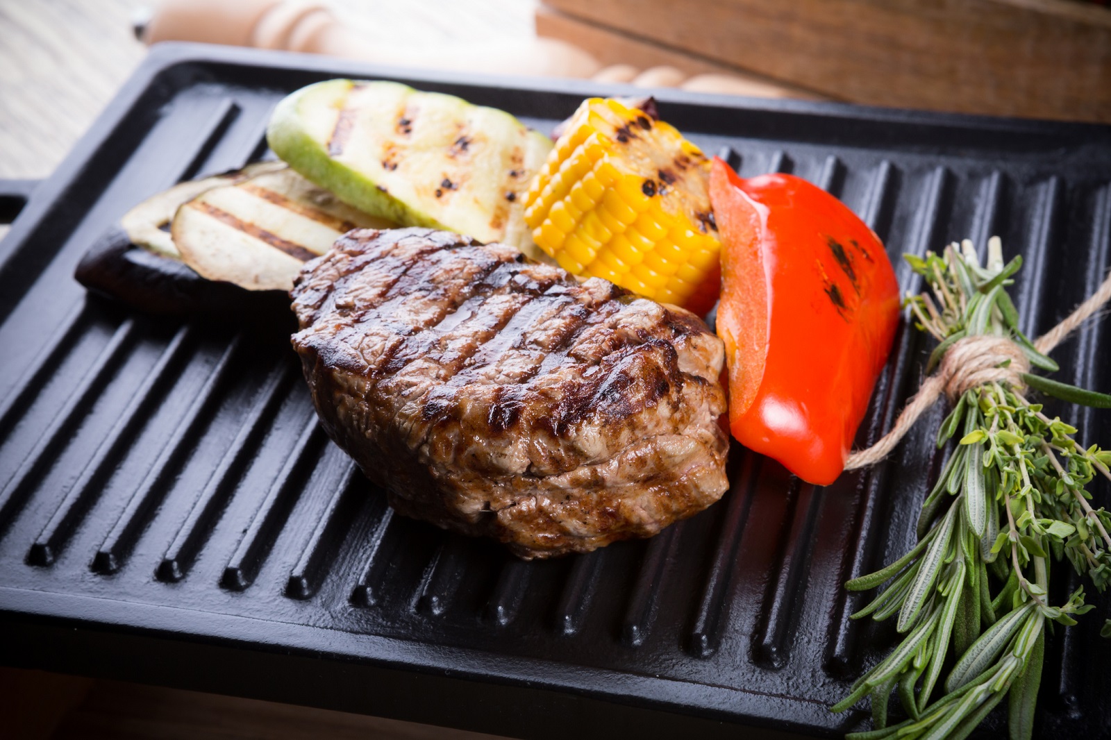 Cooked beef steak on a metal electric grill with vegetables