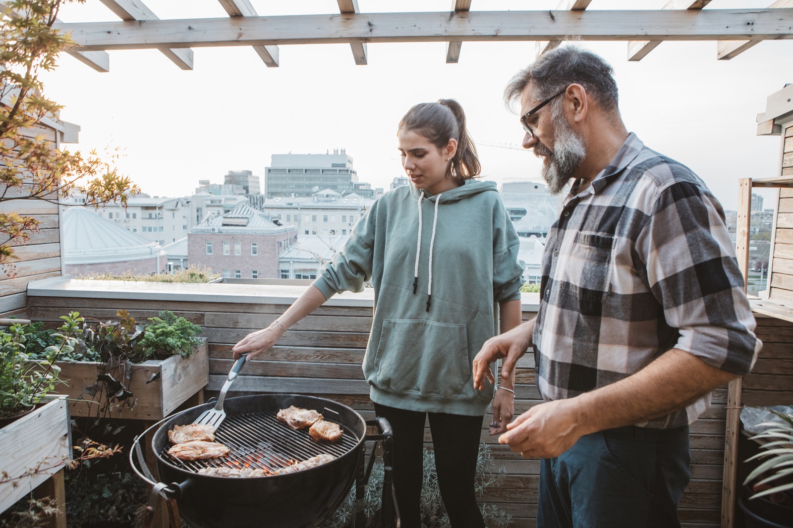 Family on terrace have barbecue during isolation period.They have great time and enjoy in sunset