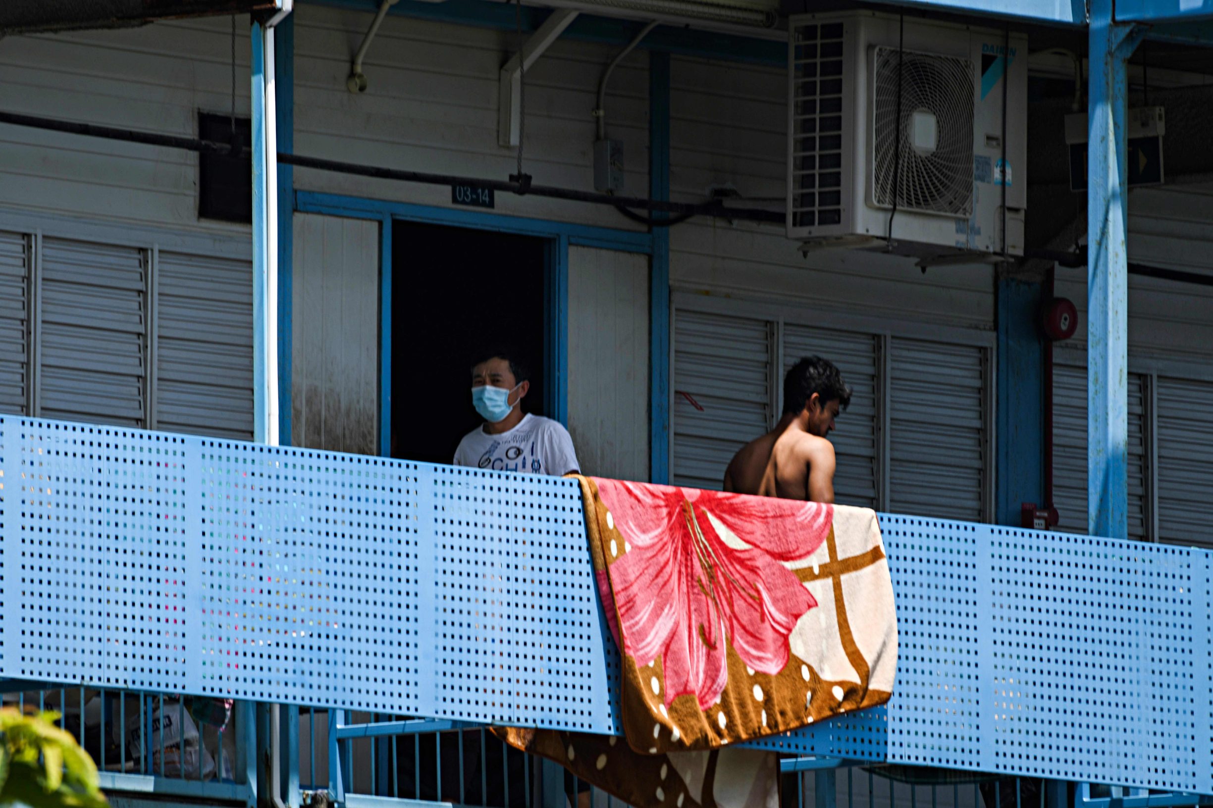 A man, wearing a face mask walks along corridor of Tuas South foreign workers dormitory that has been placed under government restriction as preventive measure against the spread of the COVID-19 coronavirus in Singapore on April 19, 2020. - Singapore imposed a mandatory stay-home order for migrant workers including in the construction sector for 14 days effective on April 20 due to coronavirus pandemic. (Photo by Roslan RAHMAN / AFP)