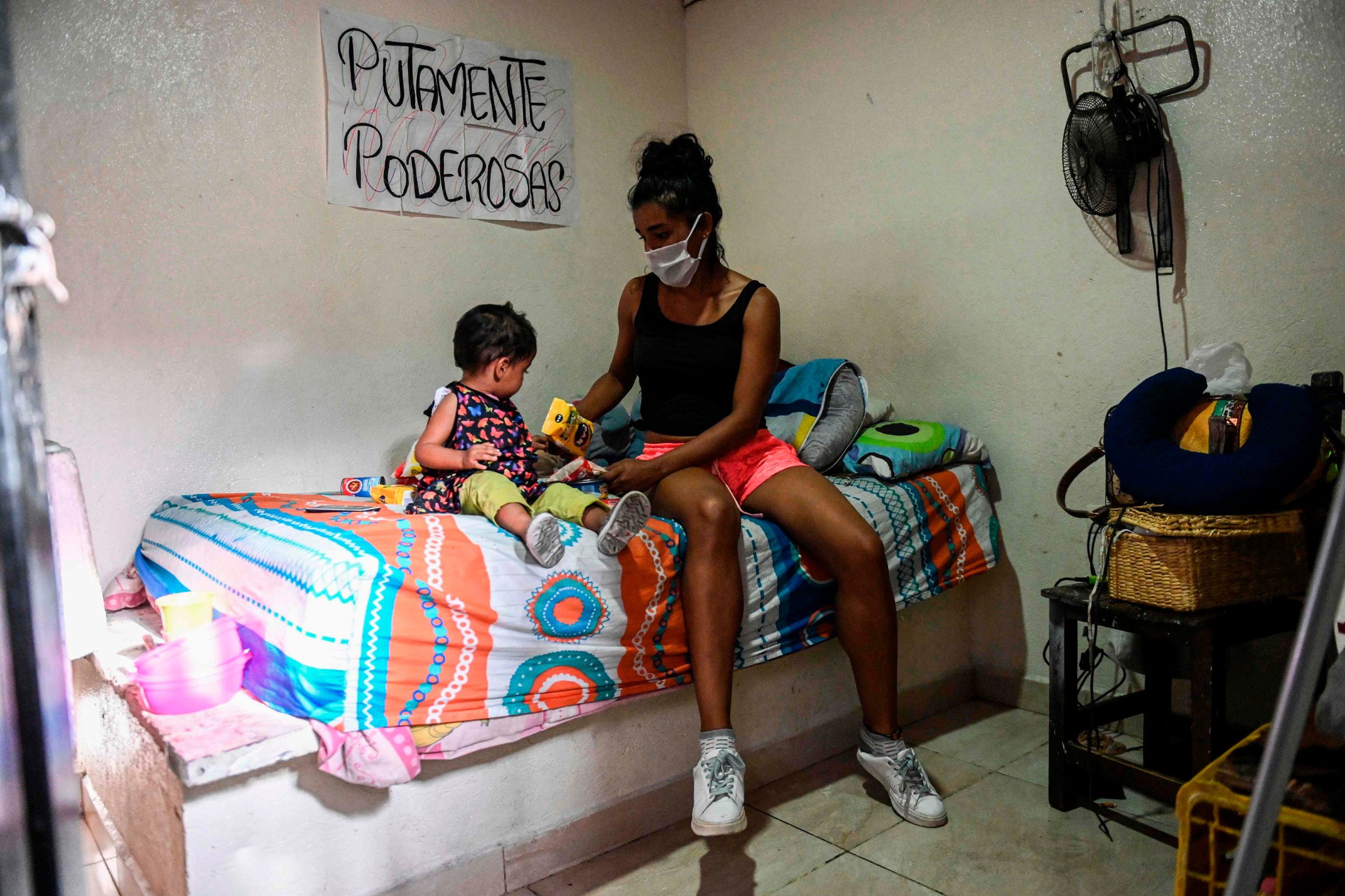 TOPSHOT - A sex worker and her daughter are pictured as they organize groceries received by activists, in her bedroom at low cost hotel located in the Tolerance zone known as the Raudal Sector, where sex workers live and work in Medellin, Colombia, on April 6, 2020. (Photo by Joaquin SARMIENTO / AFP)