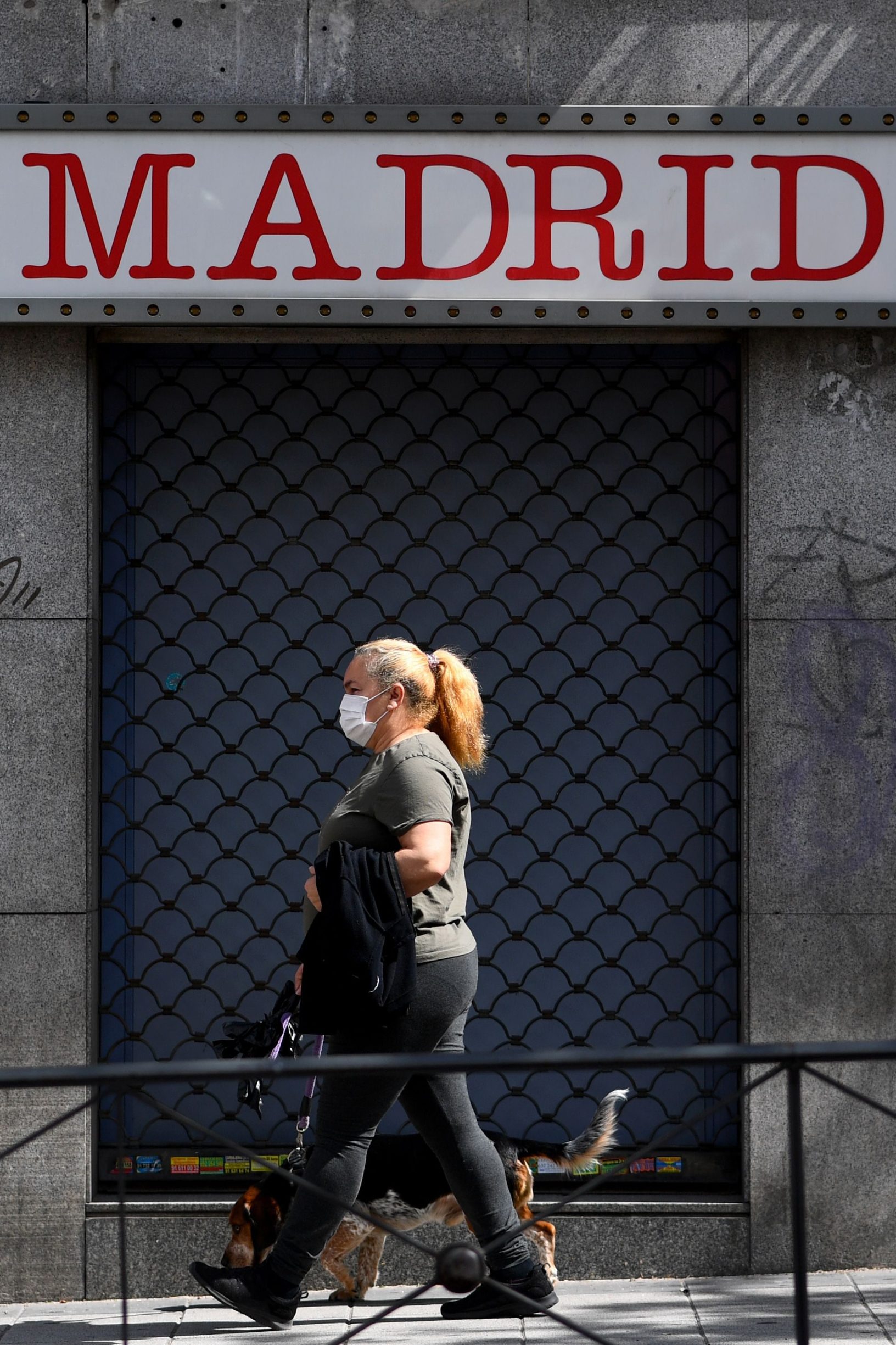 A woman, wearing a face mask, walks her dog in Puente de Vallecas, one of the poorest districts in Madrid on April 20, 2020 during a national lockdown to prevent the spread of the COVID-19 disease. - Spain said 399 people died of COVID-19 over the past 24 hours in what was the lowest daily number of deaths in four weeks, the government said. (Photo by Gabriel BOUYS / AFP)