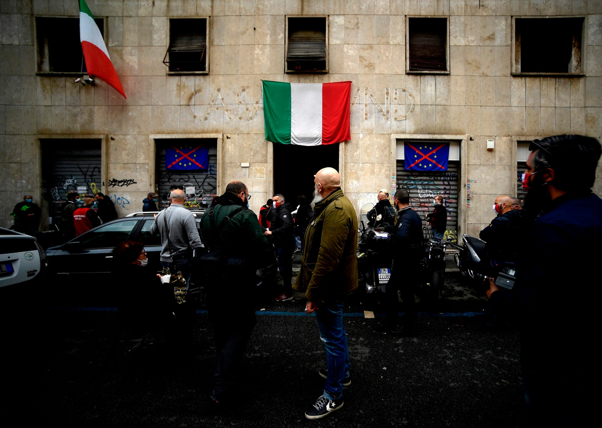 People wearing a face mask wait outside premises of Italian neo-fascist movement Casapound during a free distribution of food items on April 21, 2020 in Rome, during the lockdown aimed at curbing the spread of the COVID-19 infection, caused by the novel coronavirus. (Photo by Filippo MONTEFORTE / AFP)