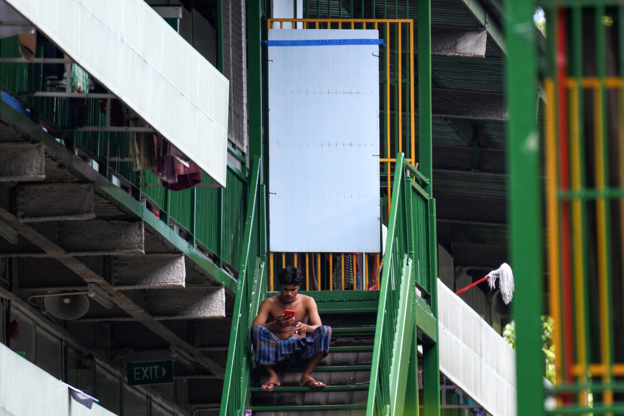 A migrant worker rest on the staircase after lunch break at the dormitories that houses foreign workers and has been made into an isolation area to prevent the spread of the COVID-19 coronavirus in Singapore on April 22, 2020. (Photo by Roslan RAHMAN / AFP)