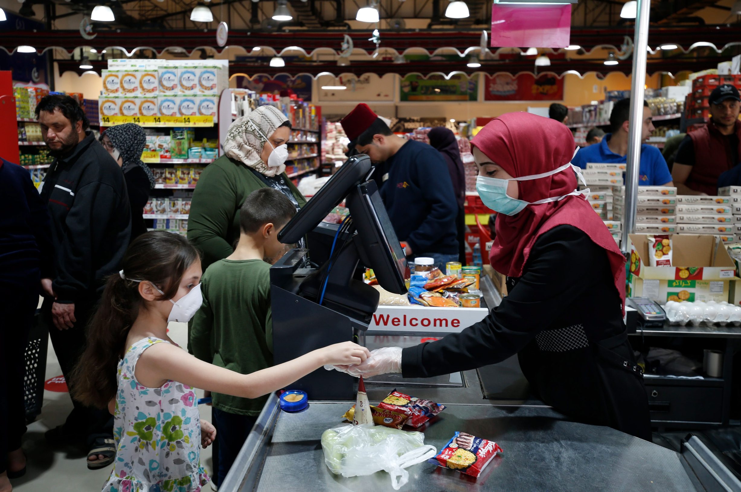 A Palestinians girl wearing a face mask buys food items at a supermarket in Gaza City ahead of the Muslim holy month of Ramadan, on April 23, 2020, during the novel coronavirus pandemic crisis. (Photo by MOHAMMED ABED / AFP)