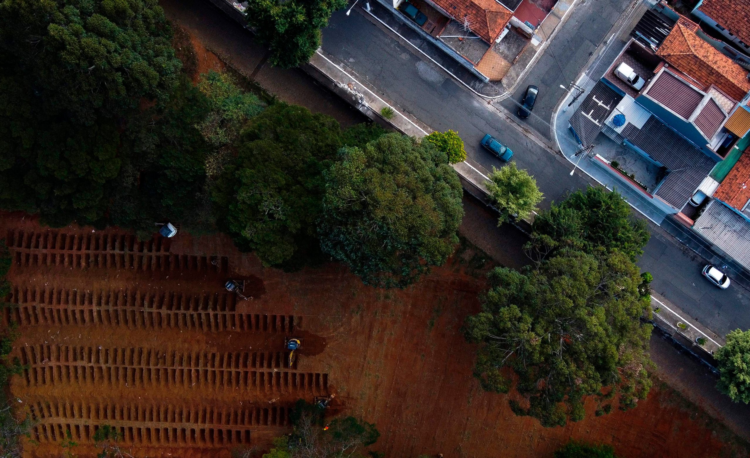 Aerial view of workers on backhoes digging graves in the Vila Formosa cemetery, due to an expected increase in deaths within the COVID-19 coronavirus pandemic, in the city of Sao Paulo, Brazil, 21 April 2020. (Photo by Miguel SCHINCARIOL / AFP)