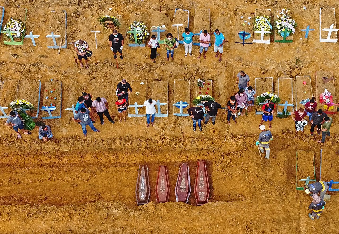 Aerial picture showing a burial taking place at an area where new graves have been dug up at the Nossa Senhora Aparecida cemetery in Manaus, in the Amazon forest in Brazil, on April 22, 2020. - The new grave area hosts suspected and confirmed victims of the COVID-19 coronavirus pandemic. More than 180,000 people in the world have died from the novel coronavirus since it emerged in China last December, according to an AFP tally based on official sources. (Photo by Michael DANTAS / AFP)
