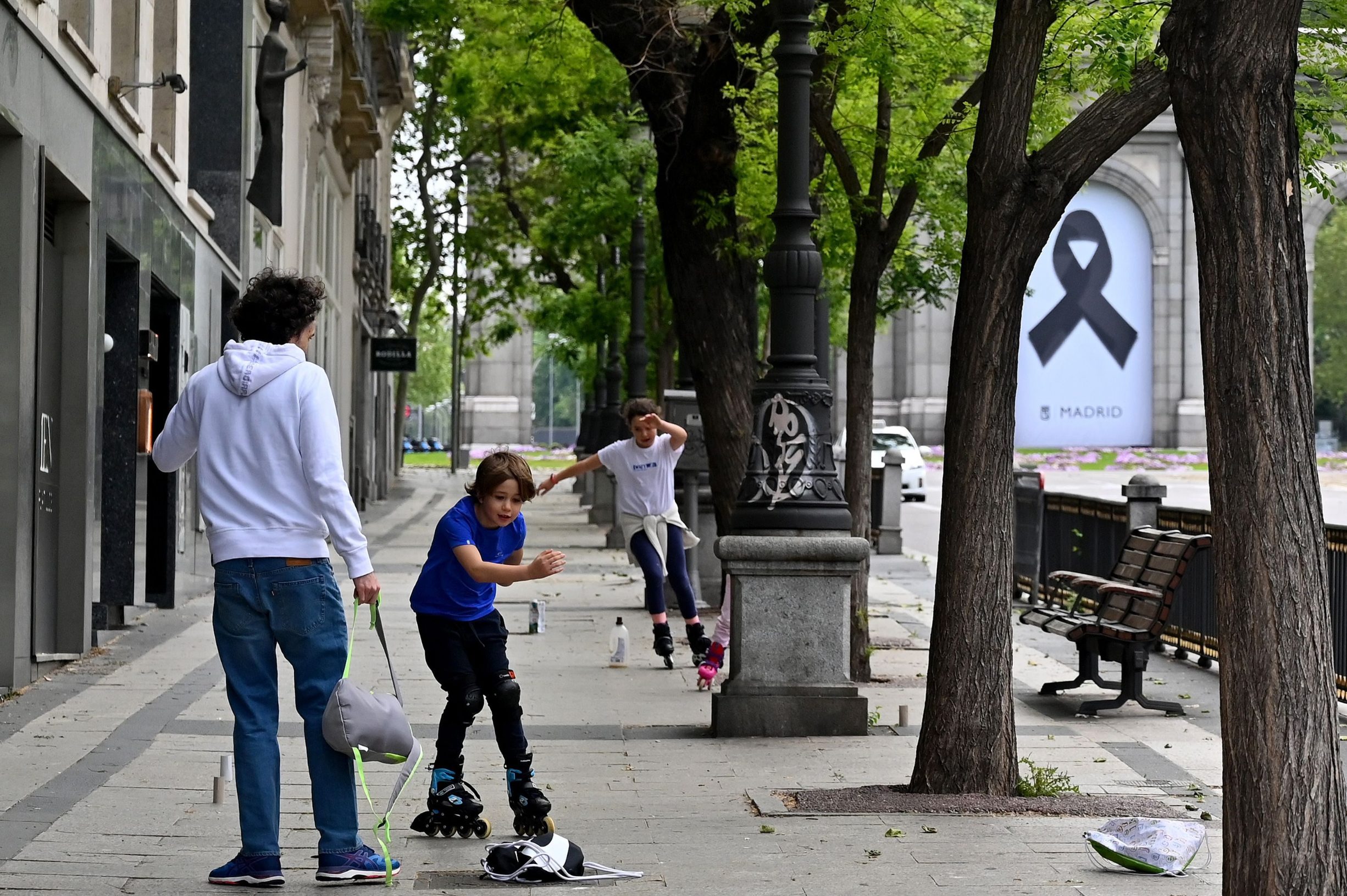 Some children skate on the pavement in Madrid on April 26, 2020 during a national lockdown to prevent the spread of the COVID-19 disease. - After six weeks stuck at home, Spain's children were being allowed out today to run, play or go for a walk as the government eased one of the world's toughest coronavirus lockdowns. Spain is one of the hardest hit countries, with a death toll running a more than 23,000 to put it behind only the United States and Italy despite stringent restrictions imposed from March 14, including keeping all children indoors. Today, with their scooters, tricycles or in prams, the children accompanied by their parents came out onto largely deserted streets. (Photo by Gabriel BOUYS / AFP)