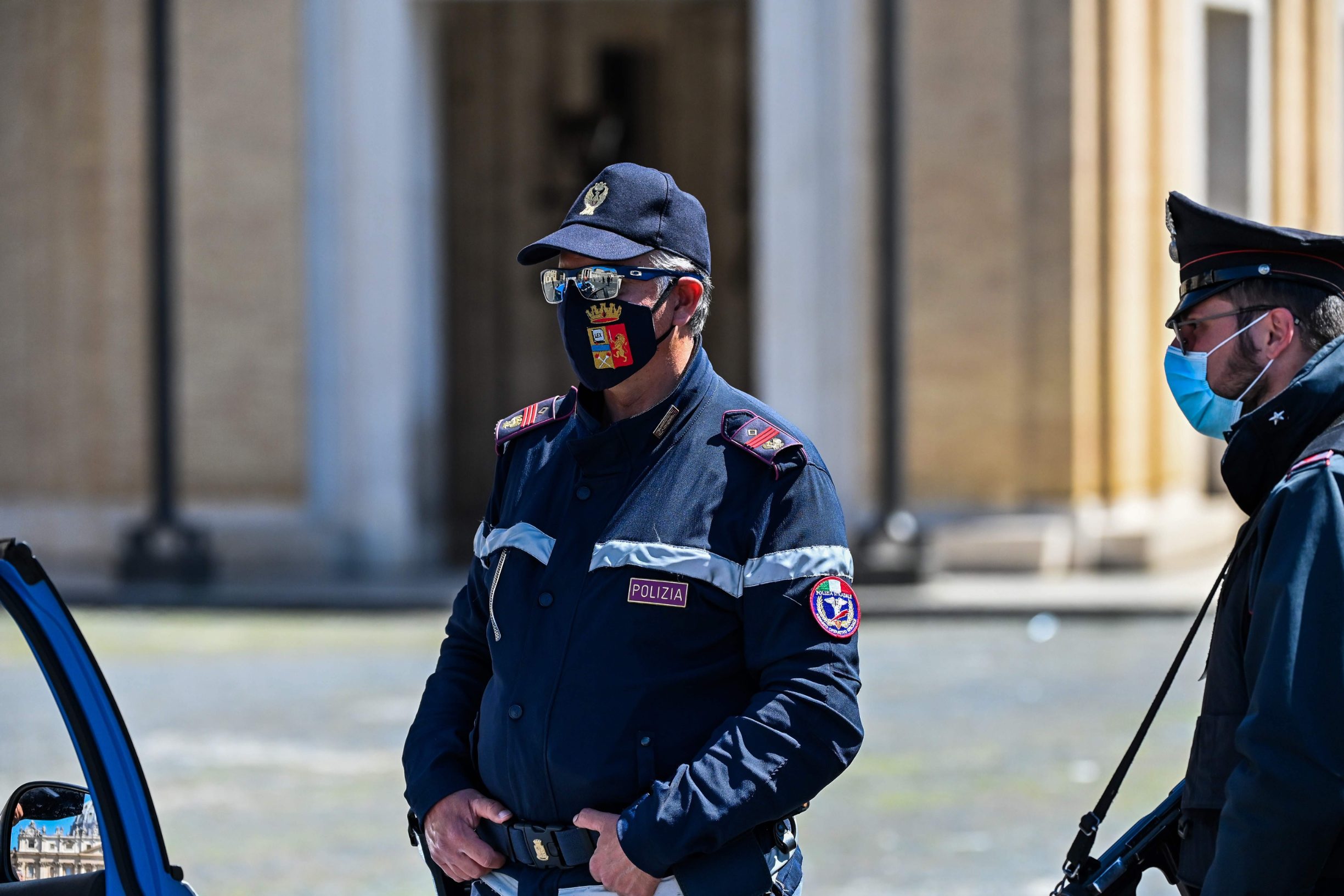 An Italian Policeman wearing a face mask with the Coats of Arms of the Italian State Police (C), and another carrying a firearm patrol at the limit between Rome in Italy and St. Peter's Square in The Vatican on April 26, 2020, during the lockdown aimed at curbing the spread of the COVID-19 infection, caused by the novel coronavirus. (Photo by ANDREAS SOLARO / AFP)