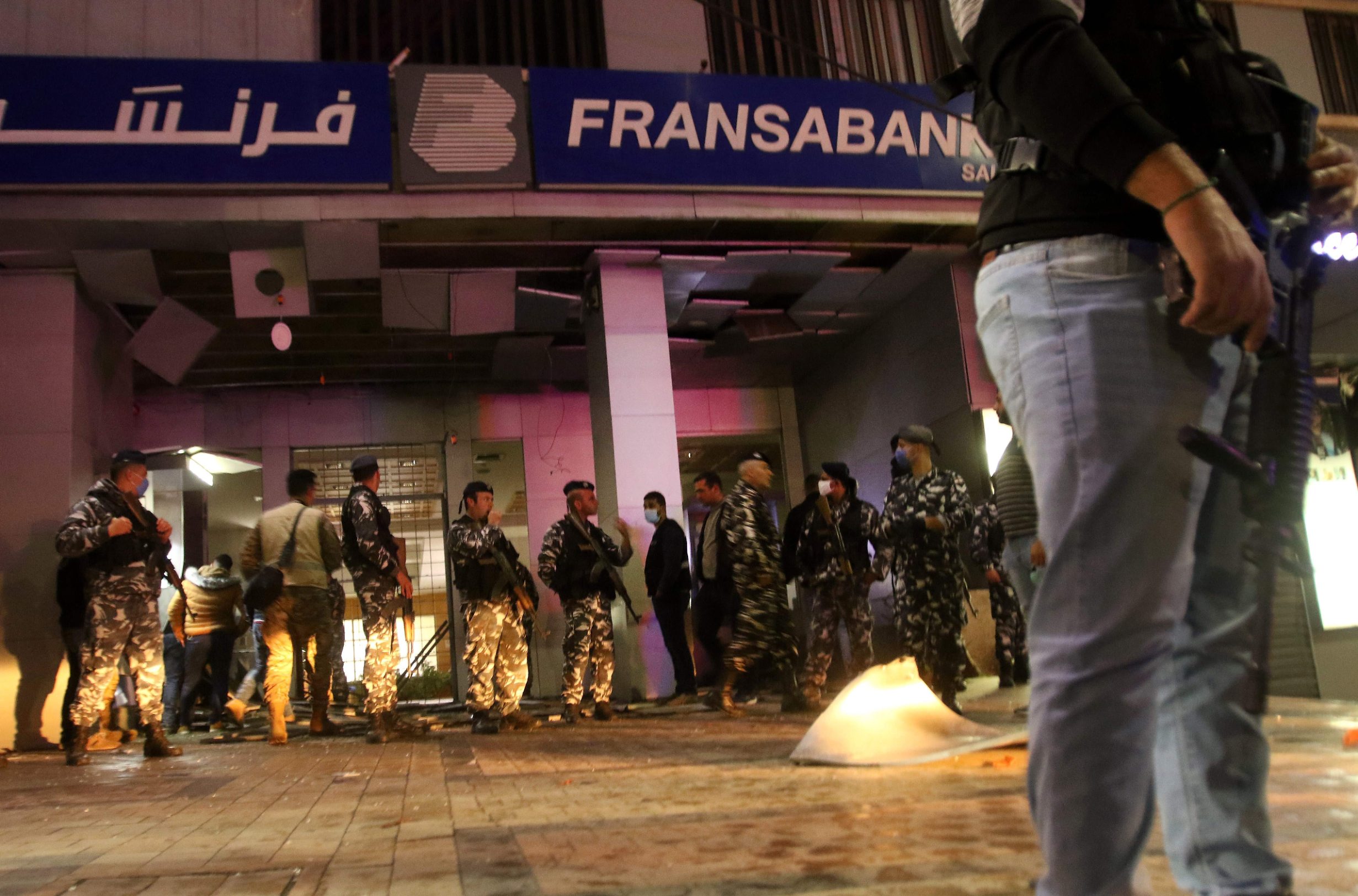 Lebanese security forces inspect the entrance of a Fransabank branch in Lebanon's southern city of Sidon on April 25, 2020, after unknown assailants targeted the bank entrance with an explosive device. - Lebanon is grappling with a severe lack of liquidity and its worst economic crisis in decades, compounded since mid-March by a lockdown to stem the novel coronavirus. Banks have gradually restricted dollar withdrawals until halting them altogether last month, and transfers abroad have been banned. In recent months, the Lebanese pound has plummeted in value from around 1,500 pounds against the US dollar to almost 3,800 on the parallel market. (Photo by Mahmoud ZAYYAT / AFP)