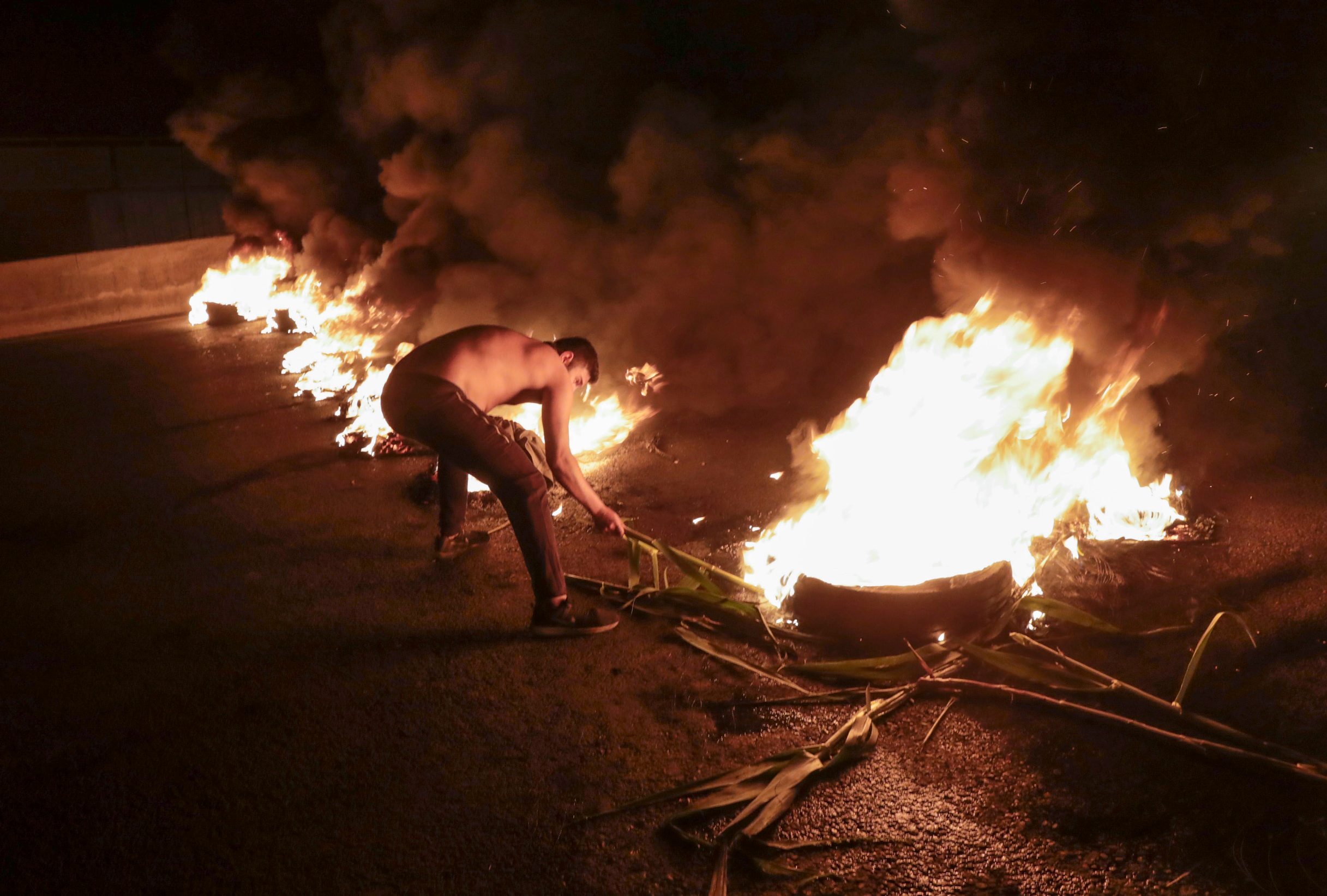 A Lebanese anti-government protester burns tyres to block the coastal highway north in the Dbayeh area, north of the capital Beirut, early on April 27, 2020, to protest the deteriorating economic situation. - Lebanon's worst economic crisis since the 1975-1990 civil war is now compounded by the coronavirus lockdown and nighttime curfew. Still, protesters have staged several daytime demonstrations recently, in continuation of a nationwide protest which erupted in October last year. (Photo by ANWAR AMRO / AFP)