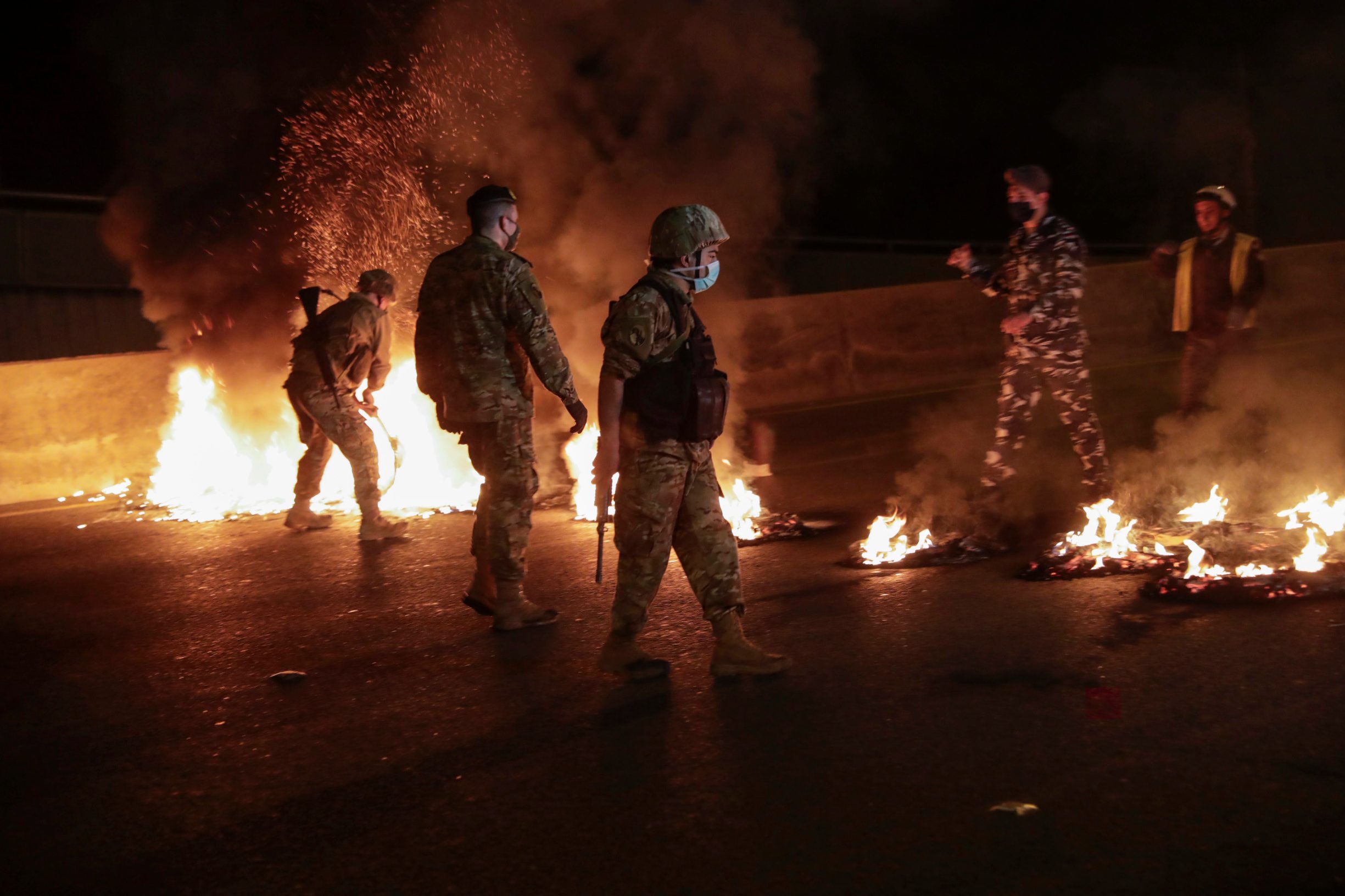 Members of the Lebanese army and security quell burning tyres which anti-government protesters have set aflame, blocking the coastal highway north in the Dbayeh area, north of the capital Beirut, early on April 27, 2020, in protest of the deteriorating economic situation. - Lebanon's worst economic crisis since the 1975-1990 civil war is now compounded by the coronavirus lockdown and nighttime curfew. Still, protesters have staged several daytime demonstrations recently, in continuation of a nationwide protest which erupted in October last year. (Photo by ANWAR AMRO / AFP)