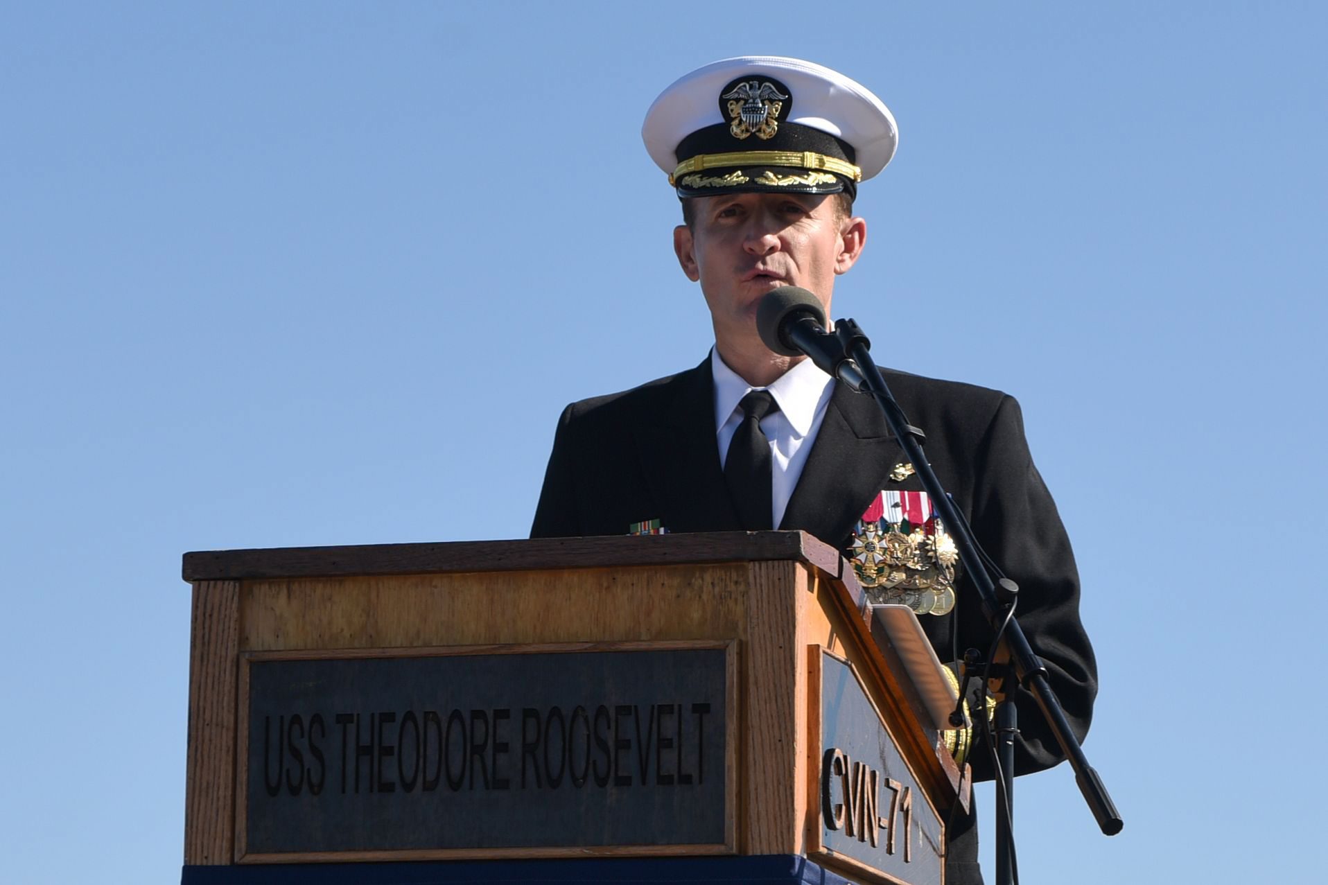 This handout photo released by the US Navy shows Captain Brett Crozier addressing the crew for the first time as commanding officer of the aircraft carrier USS Theodore Roosevelt (CVN 71) during a change of command ceremony on the ships flight deck in San Diego, California on November 1, 2019. - The Pentagon removed the captain of the coronavirus-stricken USS Theodore Roosevelt Thursday, saying he mishandled communications over how the outbreak was sweeping through the warship. Brett Crozier 