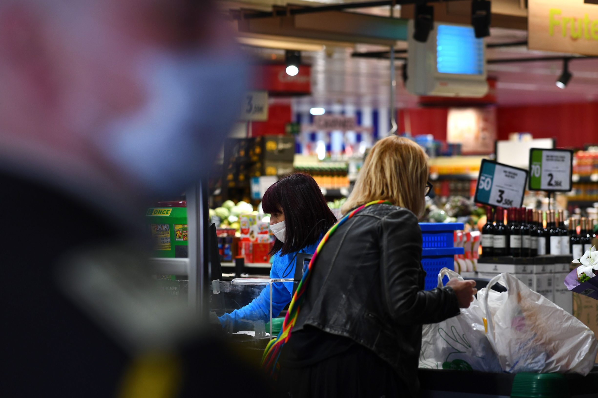 A checker wearing face mask and gloves as a preventive measure works at a supermarket on March 17, 2020 during a lockdown in Madrid as part of the country's fight against the spread of the coronavirus, COVID-19. - The Spanish government will allocate up to 100 billion euros (0 billion) for loan guarantees to businesses to buffer the economy from the damage caused by the coronavirus outbreak, Prime Minister Pedro Sanchez said today. Spain confirmed nearly 2,000 new cases of COVID-19, sending the total spiralling past 11,000, with 491 deaths, the health ministry said. (Photo by GABRIEL BOUYS / AFP)