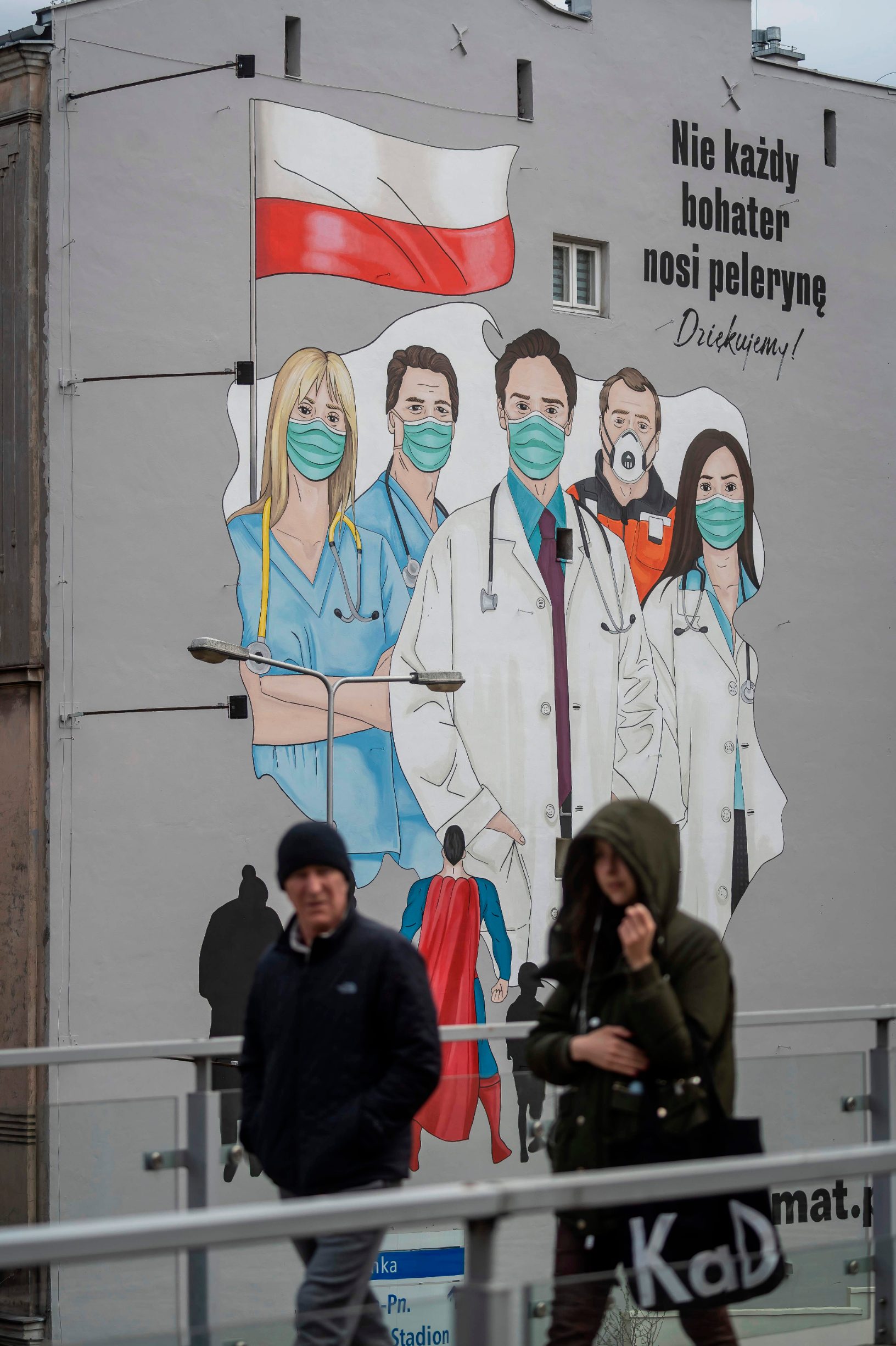 People walk passed a mural paying tribute to the sacrifice of doctors, nurses and paramedics fighting with epidemic of the new coronavirus COVID-19, in Warsaw Poland, on April 2, 2020. (Photo by Wojtek RADWANSKI / AFP)
