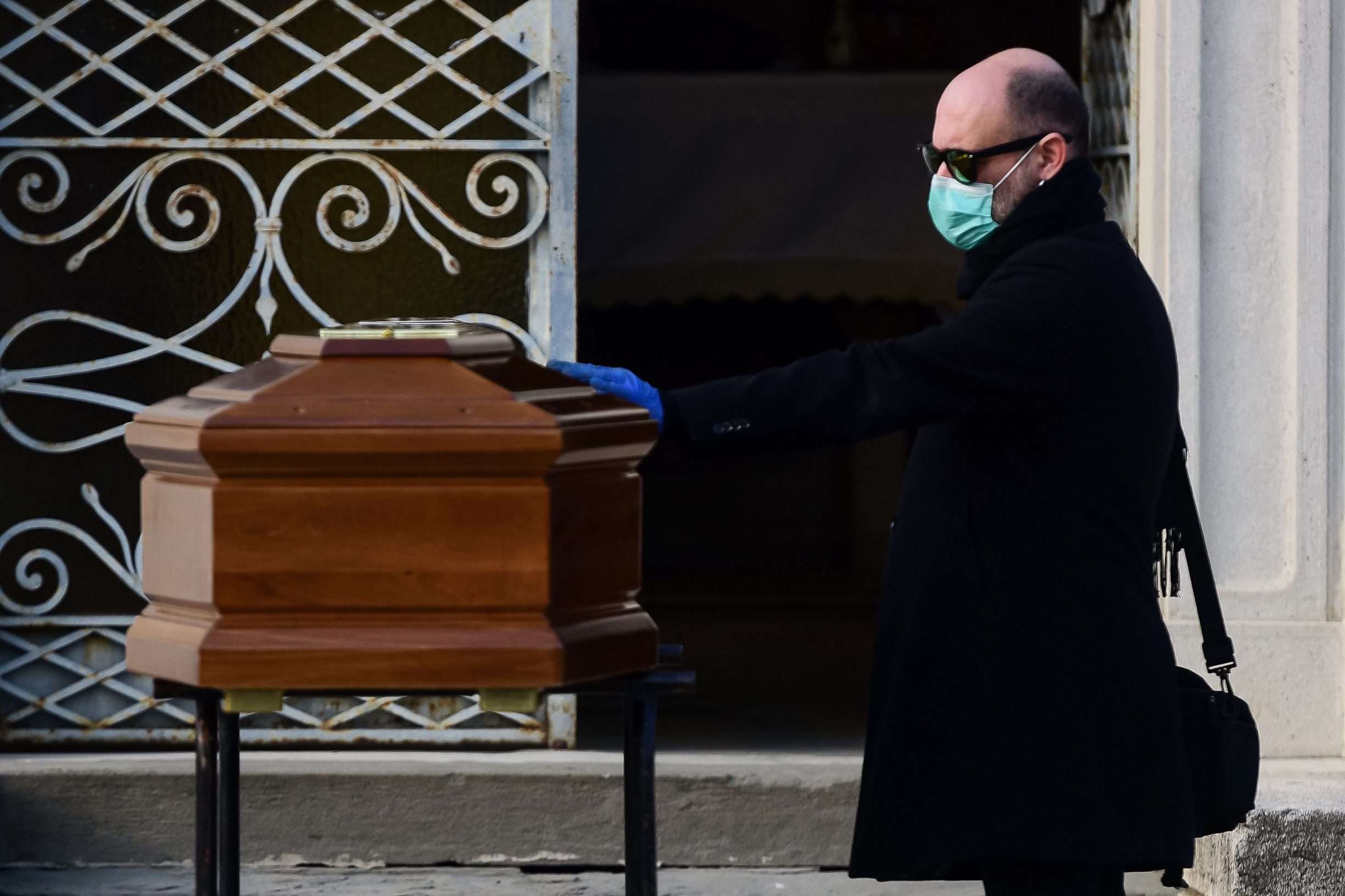 A man touches the coffin of his mother during a funeral service in the closed cemetery of Seriate, near Bergamo, Lombardy, on March 20, 2020 during the country's lockdown aimed at stopping the spread of the COVID-19 (new coronavirus) pandemic. (Photo by Piero Cruciatti / AFP)