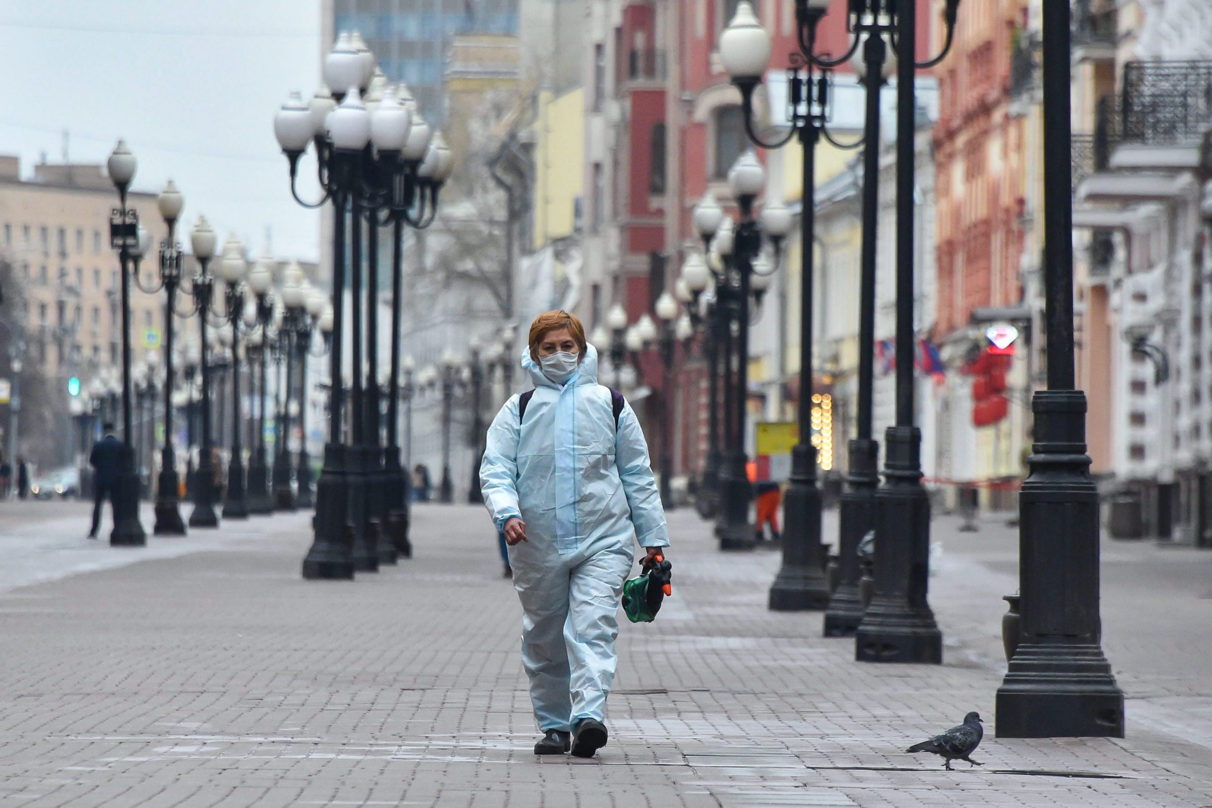 A woman wearing a protective suit carries googles and a disinfectant sprayer as she walks in downtown Moscow on April 8, 2020. (Photo by Vasily MAXIMOV / AFP)