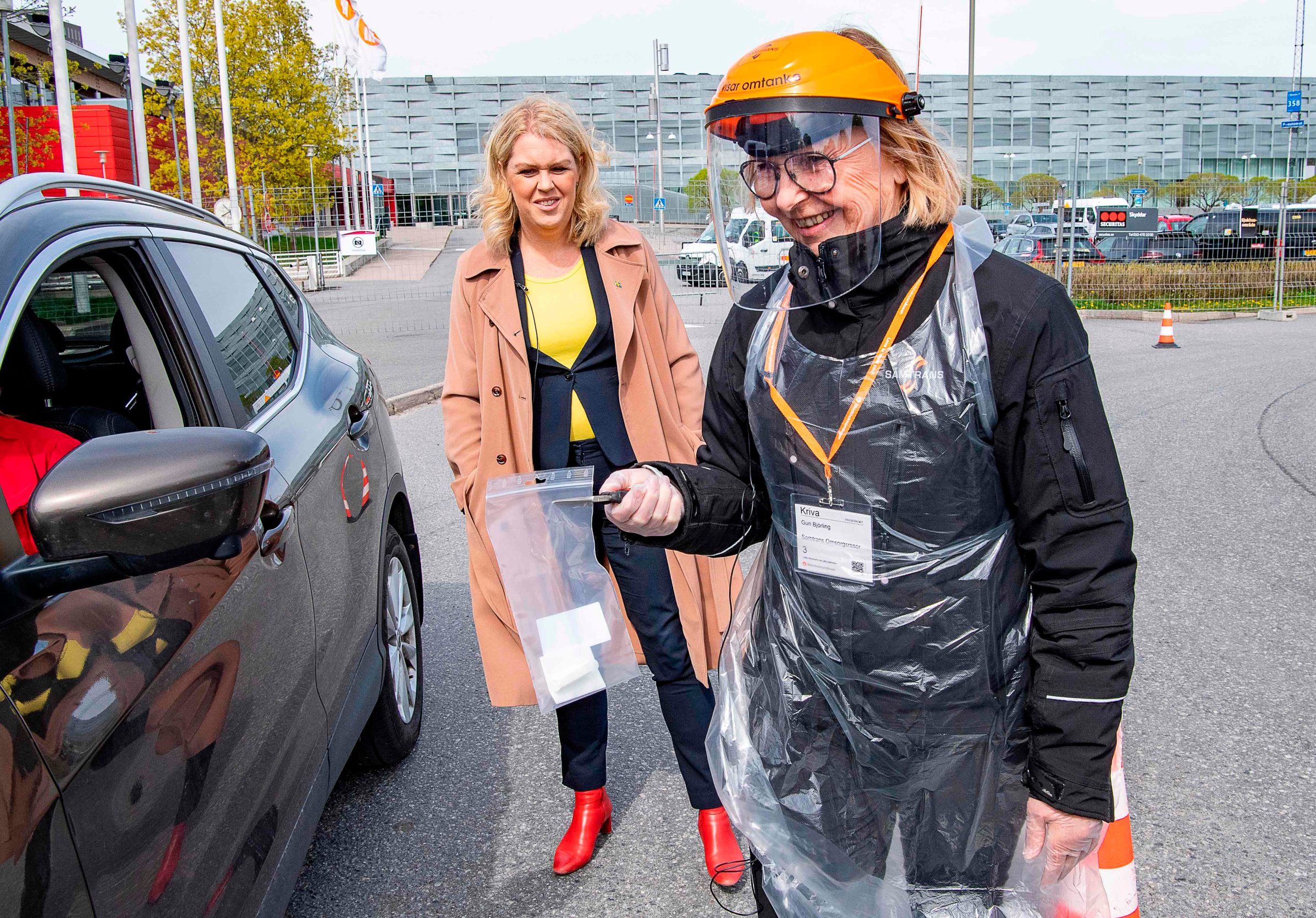 Sweden's Minister for Health and Social Affairs Lena Hallengren (C) looks on as health worker Gun Bjorling (R) administers a Covid-19 test at a drive-in-test station in Alvsjo, Stockholm, Sweden, on May 6, 2020, amid the novel coronavirus pandemic. - Several mobile test stations, primarly for health care workers, are set up around Stockhom to fight the Covid-19 disease. (Photo by Jonas EKSTROMER / TT News Agency / AFP) / Sweden OUT