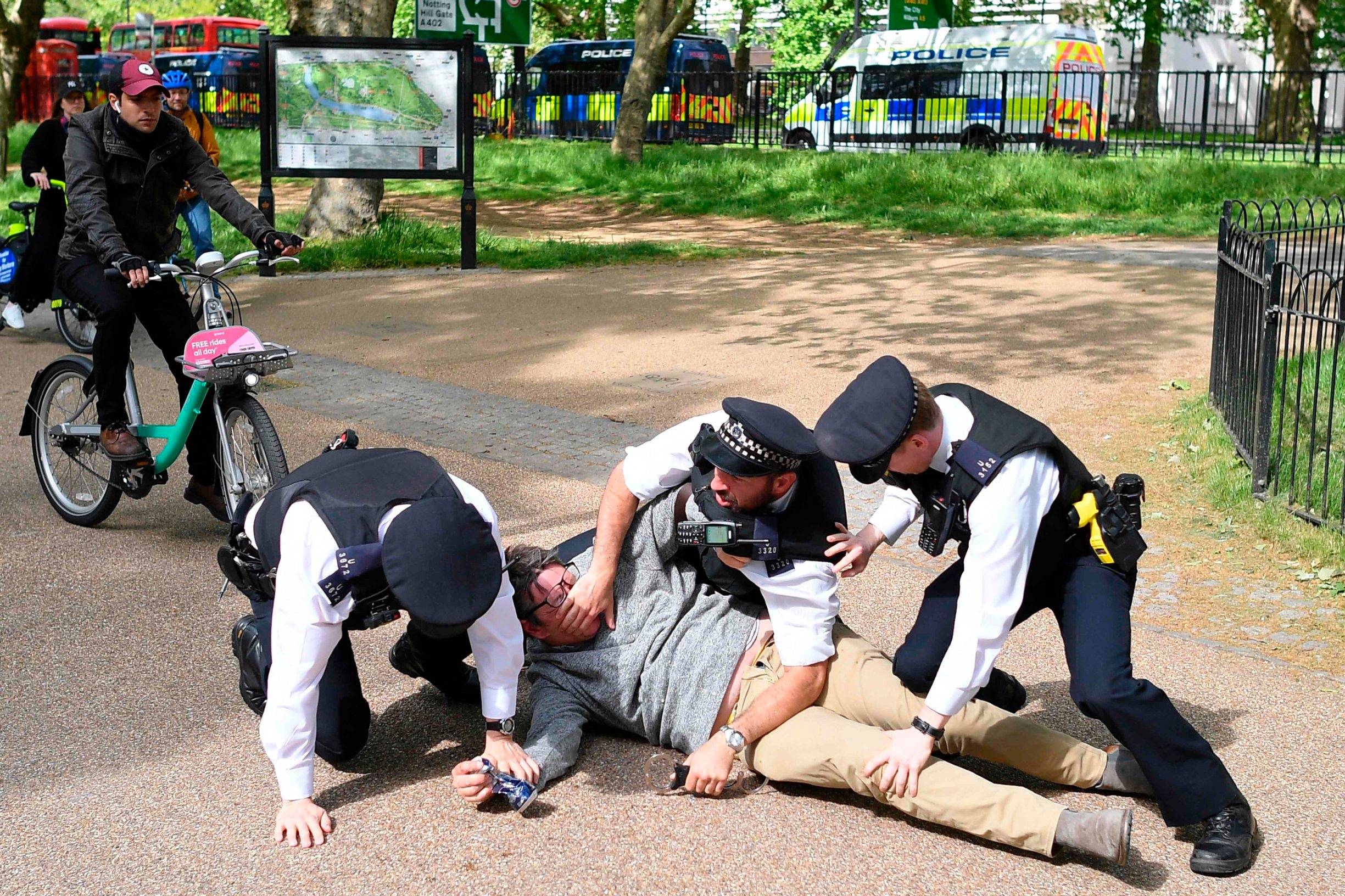 Police officers struggle to detain a man who refused to disperse from Hyde Park in London on May 16, 2020, following an easing of lockdown rules in England during the novel coronavirus COVID-19 pandemic. - People are being asked to 