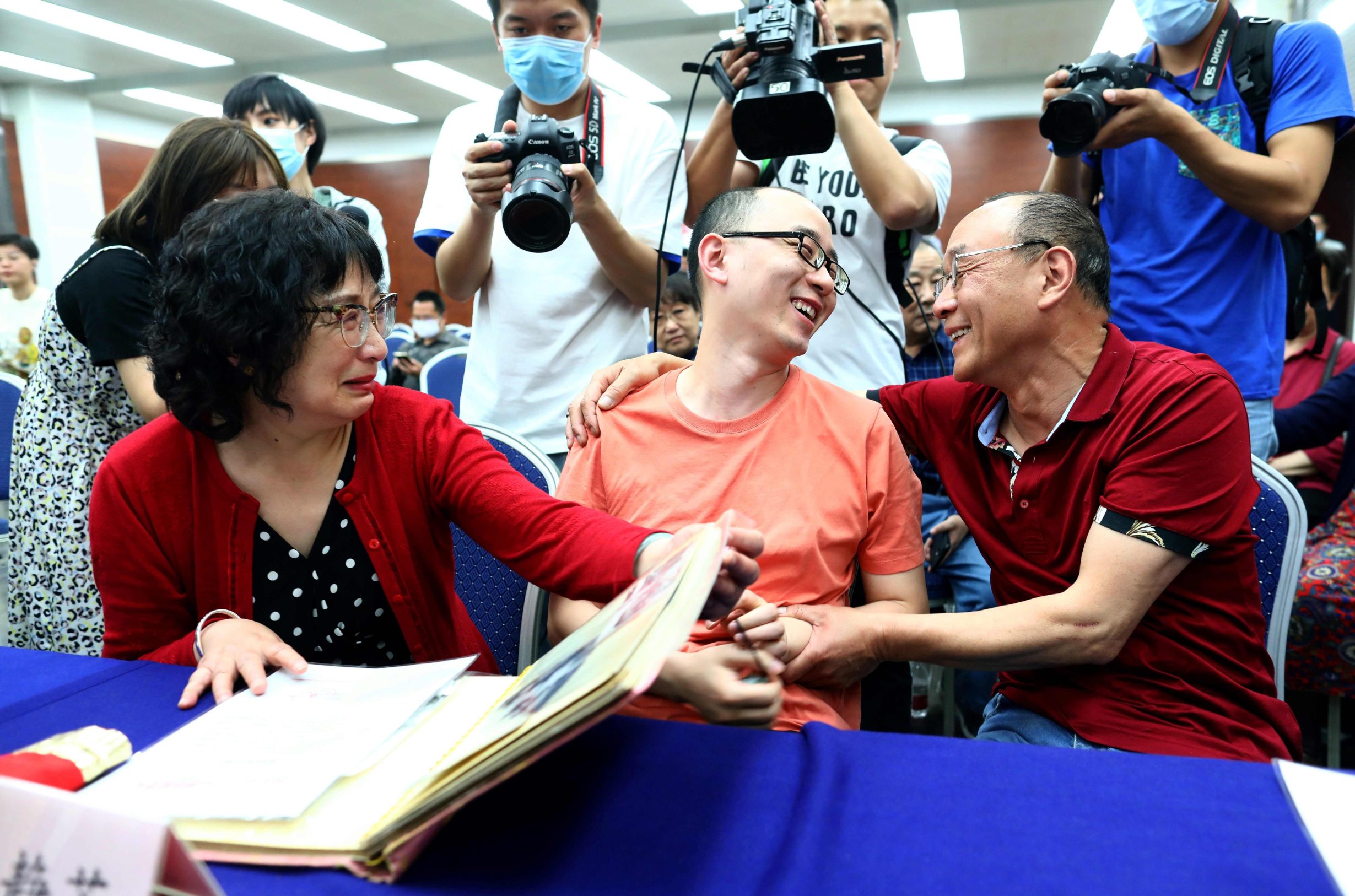 This photo taken on May 18, 2020 shows Mao Yin (C) speaking with his mother Li Jingzhi (L) and father Mao Zhenping (R) in Xian, in China's northern Shaanxi province. - A Chinese man who was kidnapped as a toddler 32 years ago has been reunited with his biological parents, after police used facial recognition technology to track him down. (Photo by STR / AFP) / China OUT