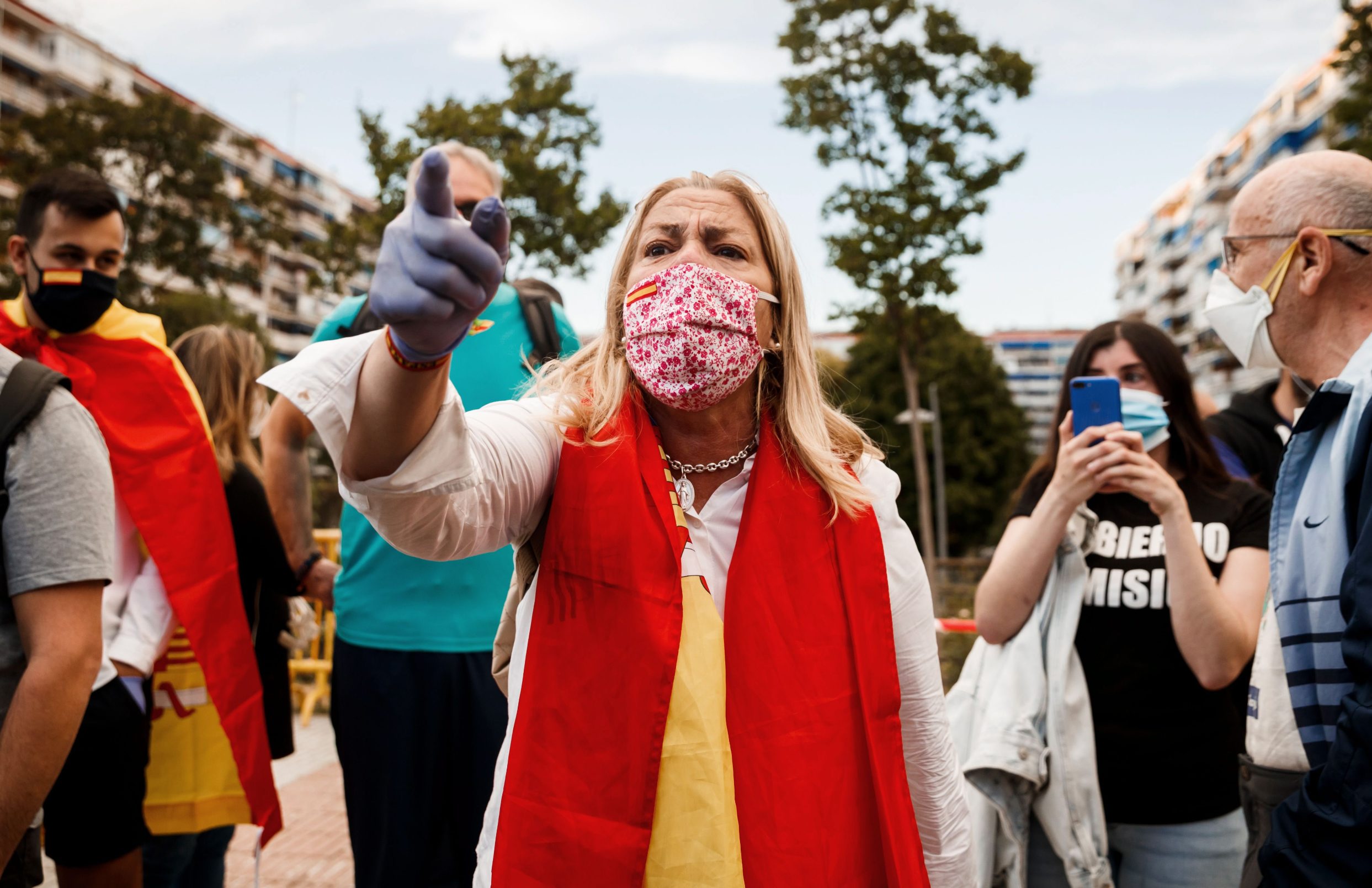 TOPSHOT - A woman wrapped in a Spanish flag shouts against counter protestrs during a protest against the government's handling of the coronavirus crisis, on May 19, 2020, in Alcorcon, near Madrid. - Most Spaniards support the lockdown and believe it should be extended, a survey showed, despite angry protests in Madrid and elsewhere denouncing the government's handling of the coronavirus crisis. Renewed four times, the state of emergency has let the government impose some of the world's tightest restrictions on Spain's nearly 47 million population, although it has since begun a cautious rollback which is due to finish by late June. (Photo by Baldesca SAMPER / AFP)