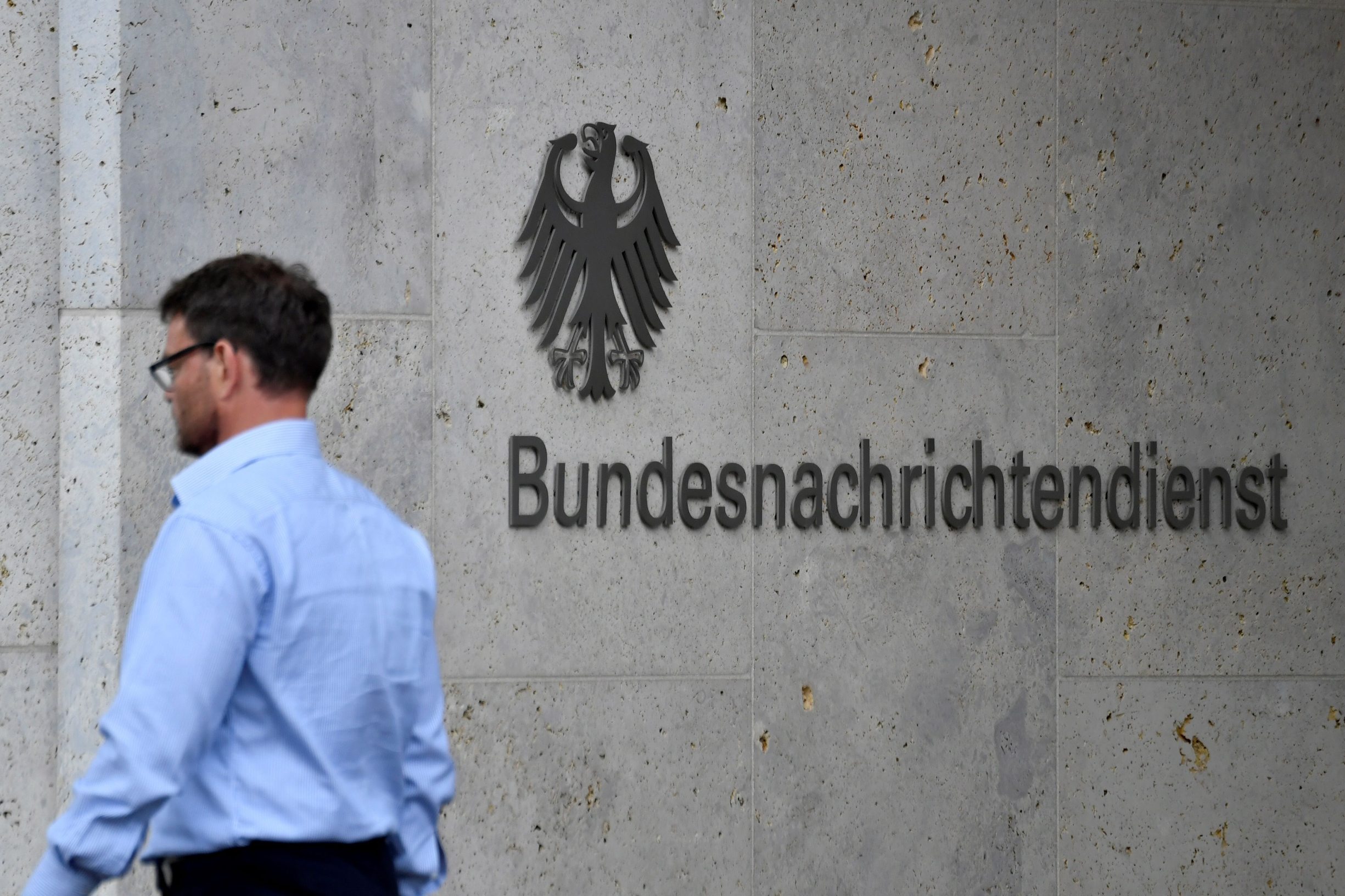 A picture taken on May 19, 2020 shows an employee walking past the name of German Federal Intelligence Service (BND) at its headquartersin Berlin. - Germany's foreign intelligence service (BND) is not allowed to spy on internet data from foreigners abroad, the country's top court ruled on May 19, 2020 siding with a complaint brought by journalists overseas. (Photo by John MACDOUGALL / AFP)