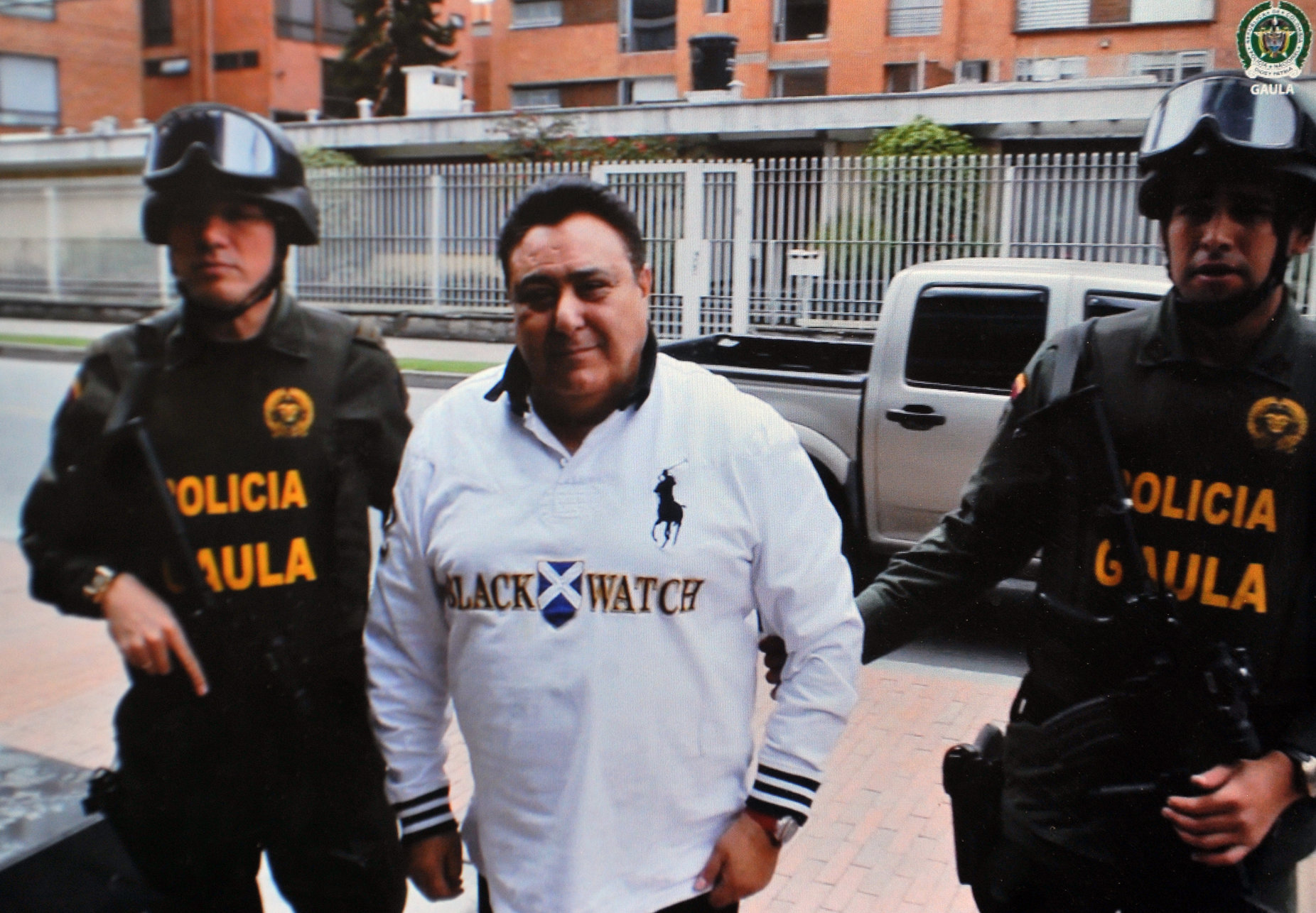Screen image taken at the headquarters of the National Police in Bogota, on July 6, 2013, from a Police video showing Colombian police officers escorting Roberto Pannunzi (65),  an Italian mafia capo allegedly the world biggest cocaine trafficker who was arrested on the eve. Pannunzi  who fled from a Rome prison in 2010, was detained in a shopping mall in Bogota with a fake Venezuelan identity card in a joint operation by Colombian police and the US Drug Enforcement Administration (DEA) and was deported on Friday night to Italy. AFP PHOTO/Guillermo LEGARIA (Photo by GUILLERMO LEGARIA / AFP)