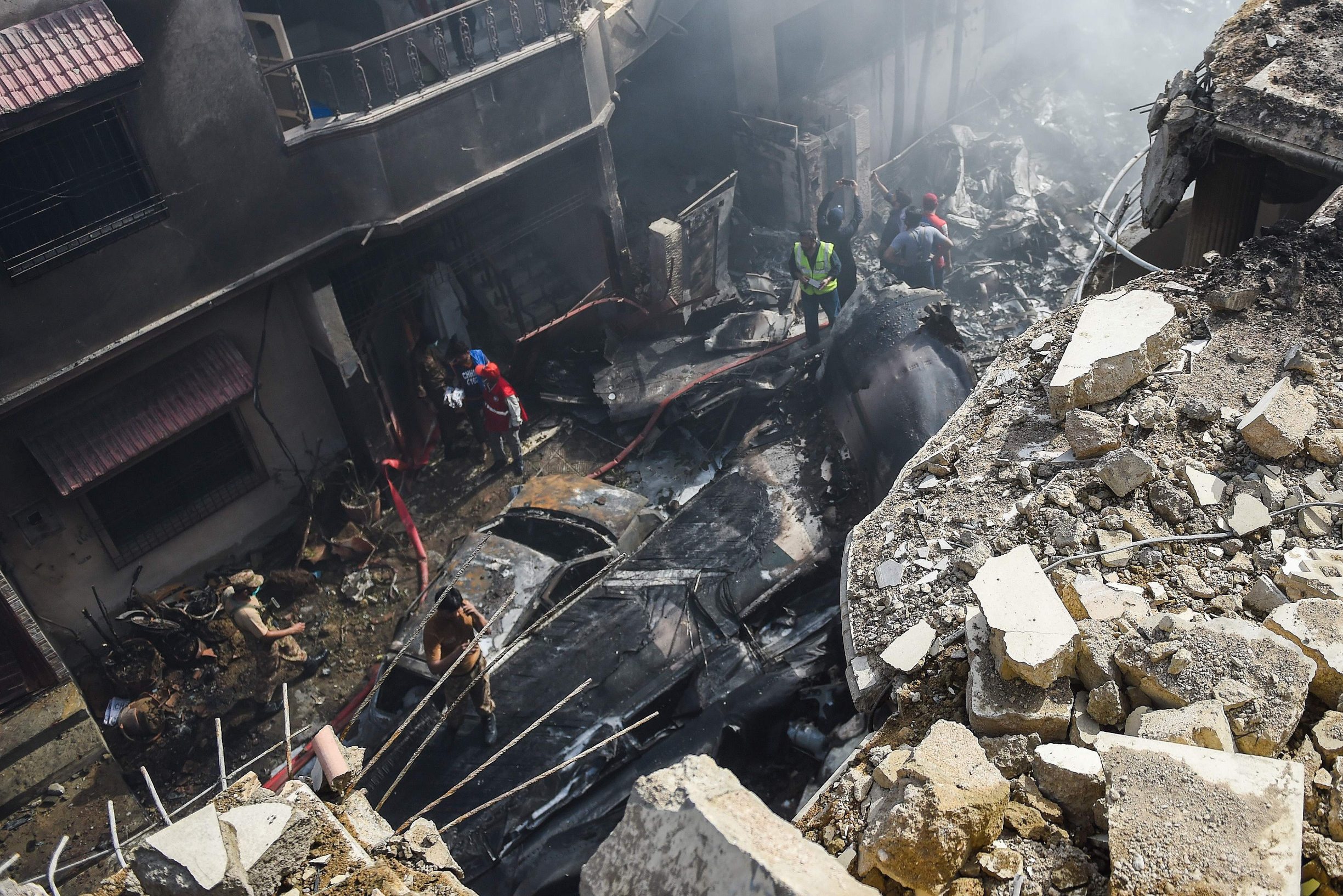 Rescue workers gather at the site after a Pakistan International Airlines aircraft crashed in a residential area in Karachi on May 22, 2020. - A Pakistani plane with nearly 100 people on board crashed into a residential area in the southern city of Karachi on May 22, killing several people on the ground. (Photo by Rizwan TABASSUM / AFP)