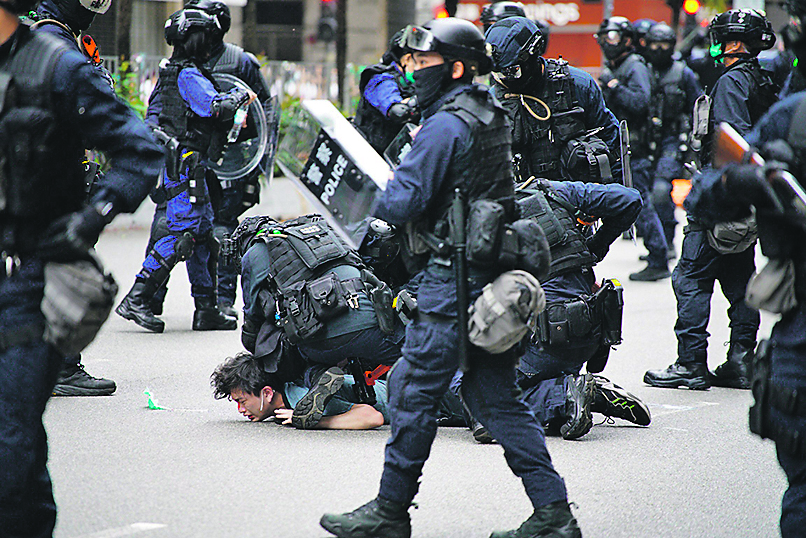 TOPSHOT - Police special tactical squad detain a protester (C) in Wanchai, Hong Kong on May 24, 2020, as thousands of demonstrators took to the streets to protest against a national security law. - The proposed legislation is expected to ban treason, subversion and sedition, and follows repeated warnings from Beijing that it will no longer tolerate dissent in Hong Kong, which was shaken by months of massive, sometimes violent anti-government protests last year. (Photo by Yan ZHAO / AFP)